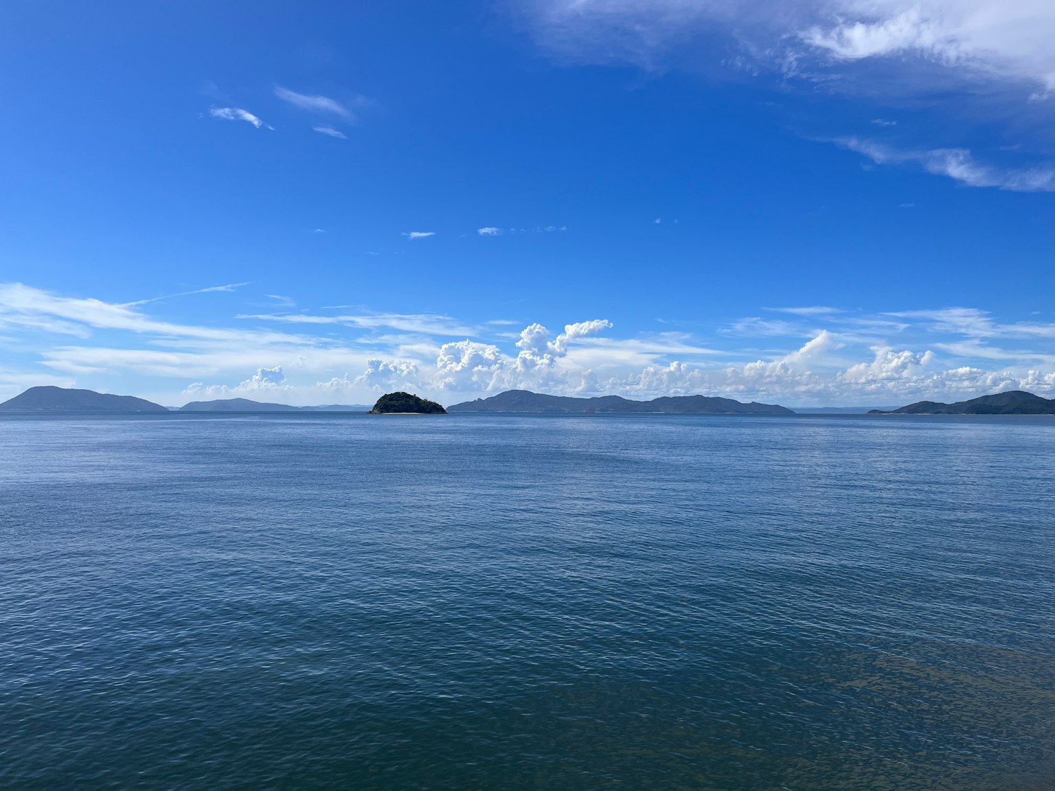 Un paisaje marino sereno con cielos azules y aguas tranquilas islas distantes visibles