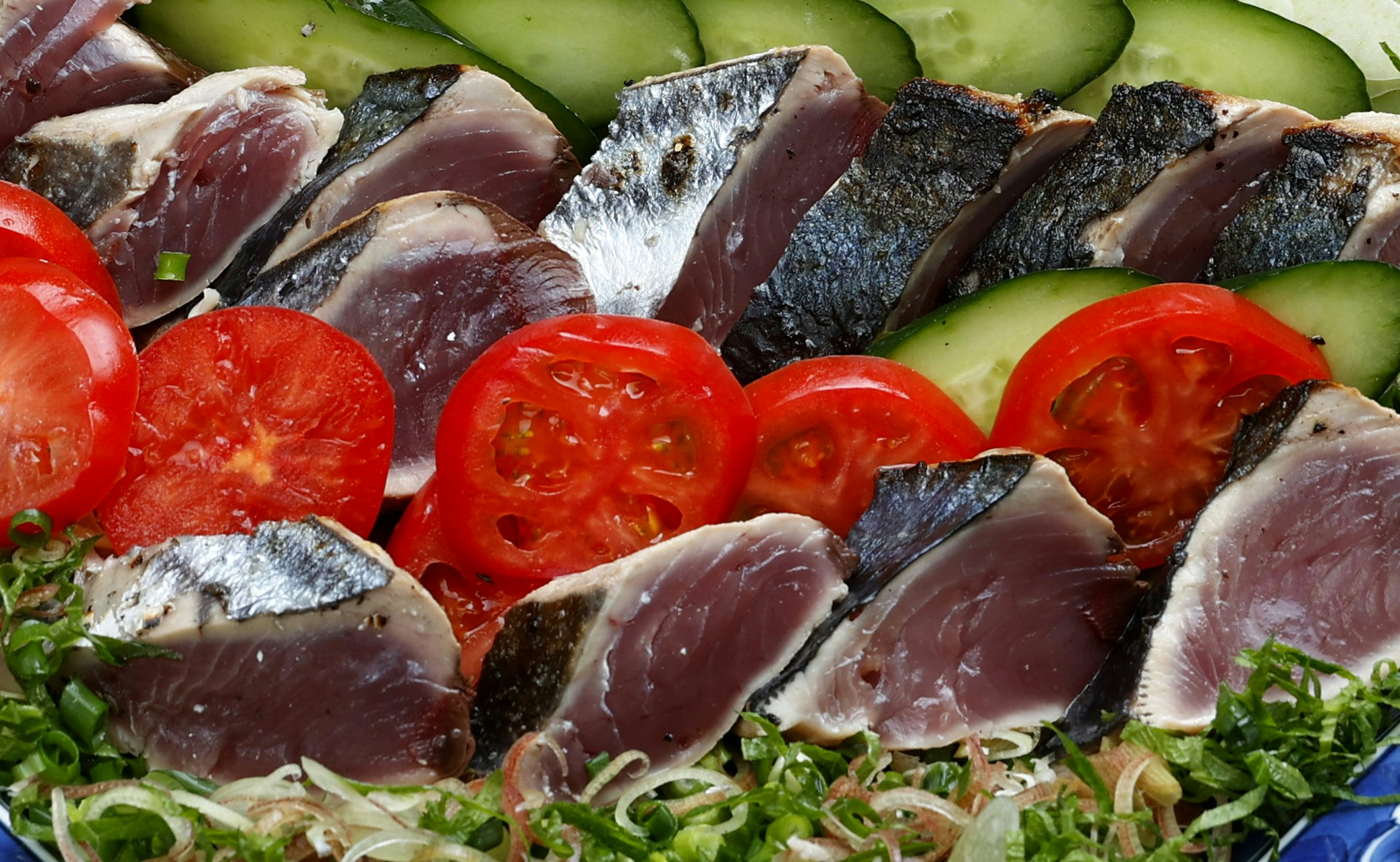Scheiben von gepökeltem Fleisch und Lachs mit Gemüse und Kräutern angerichtet