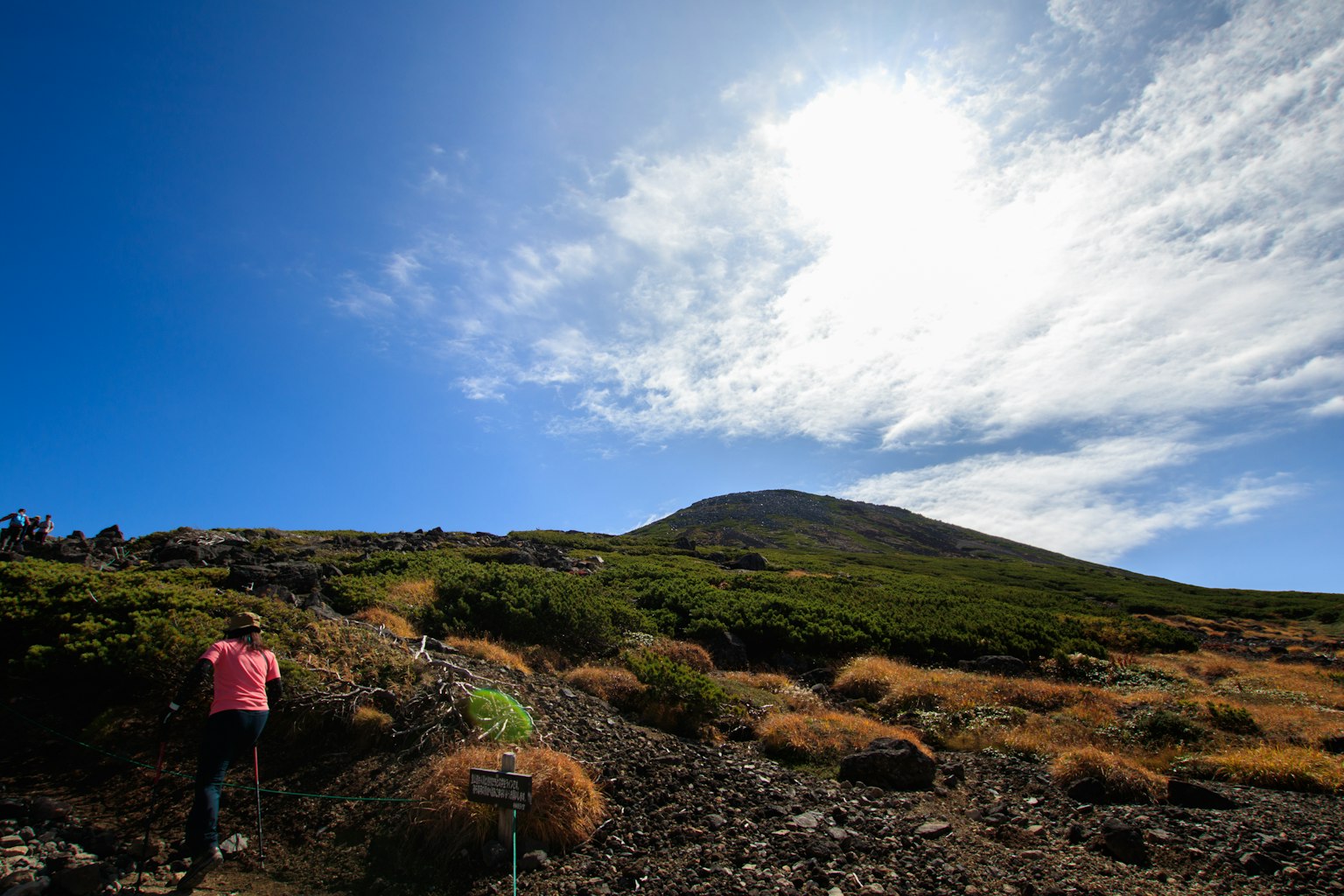 Senderista subiendo una montaña bajo un cielo azul brillante