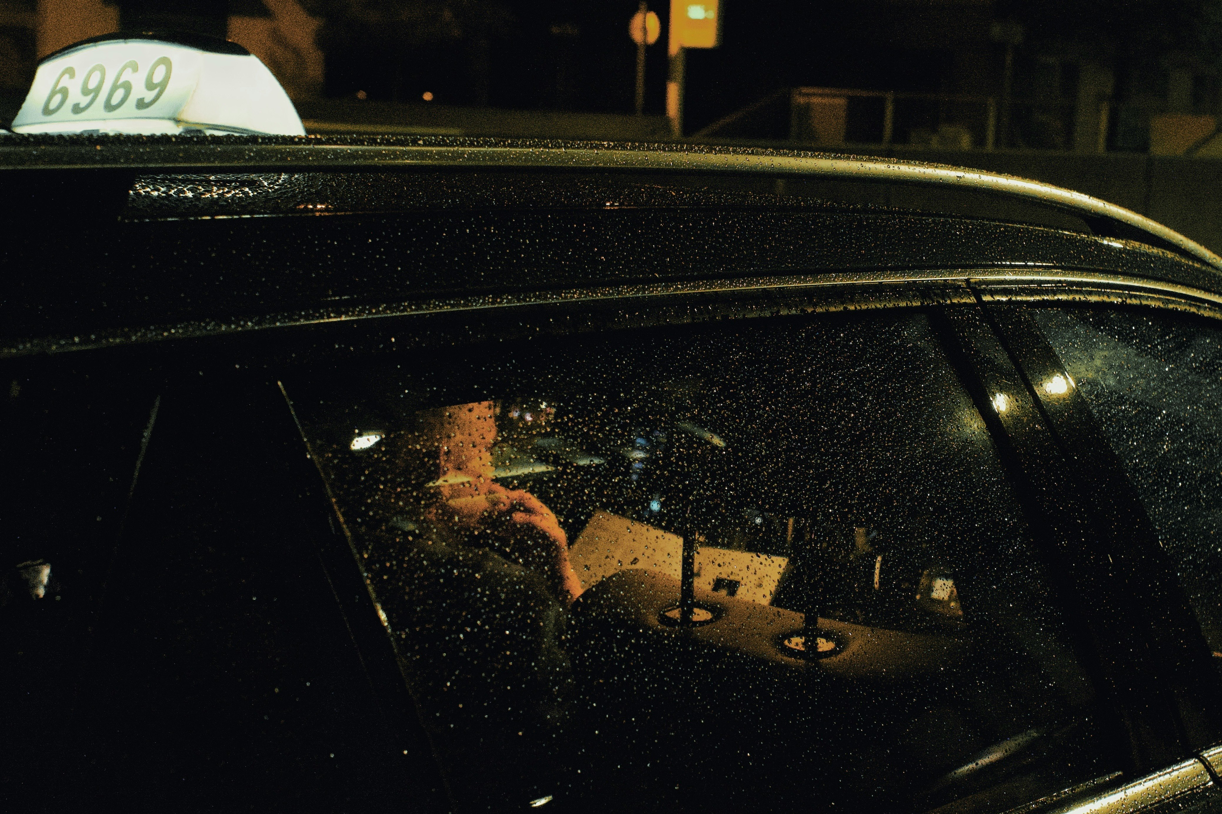 雨の夜、タクシーの中で本を読む運転手
