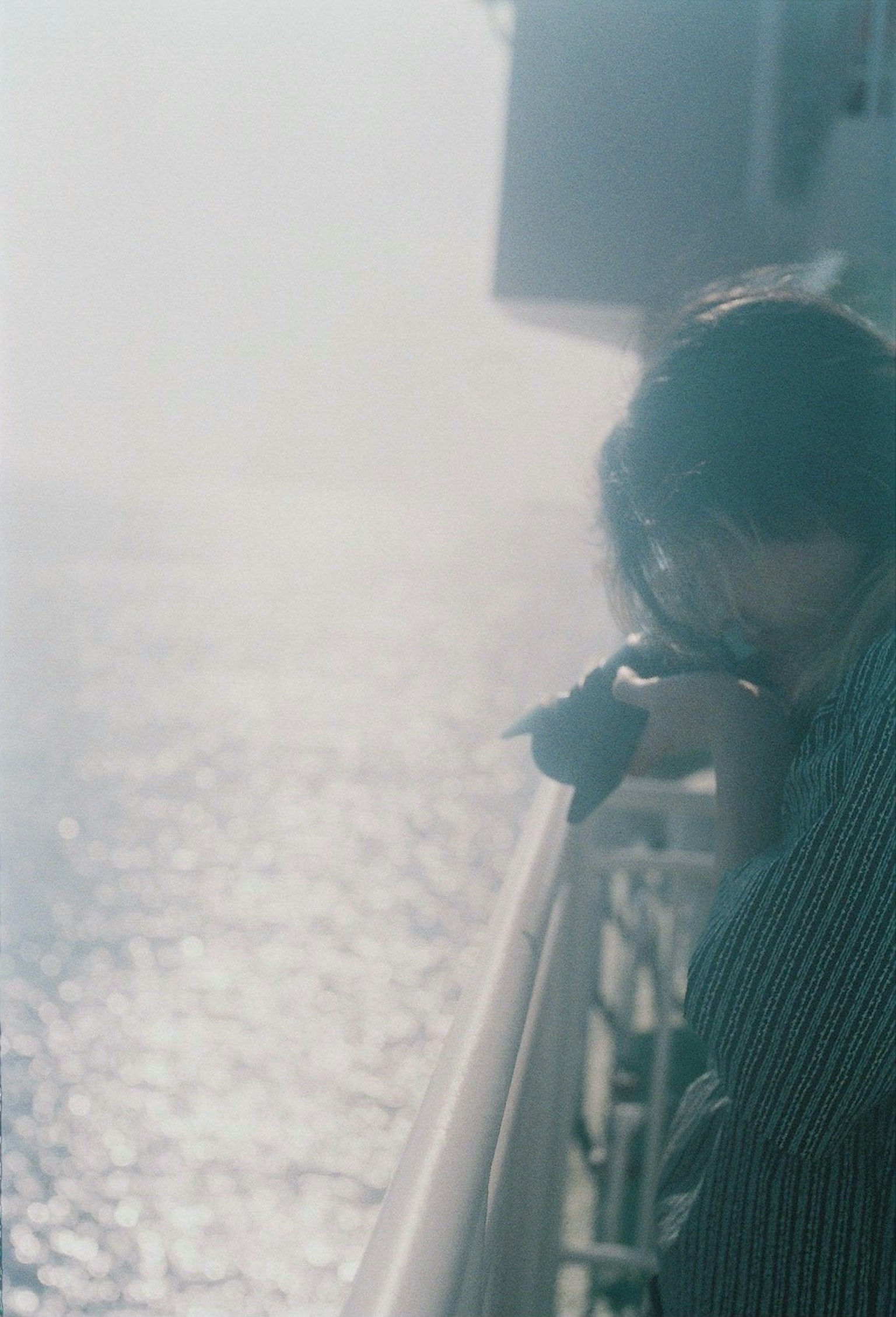 海を見つめる人物のぼんやりしたシルエットと光の反射