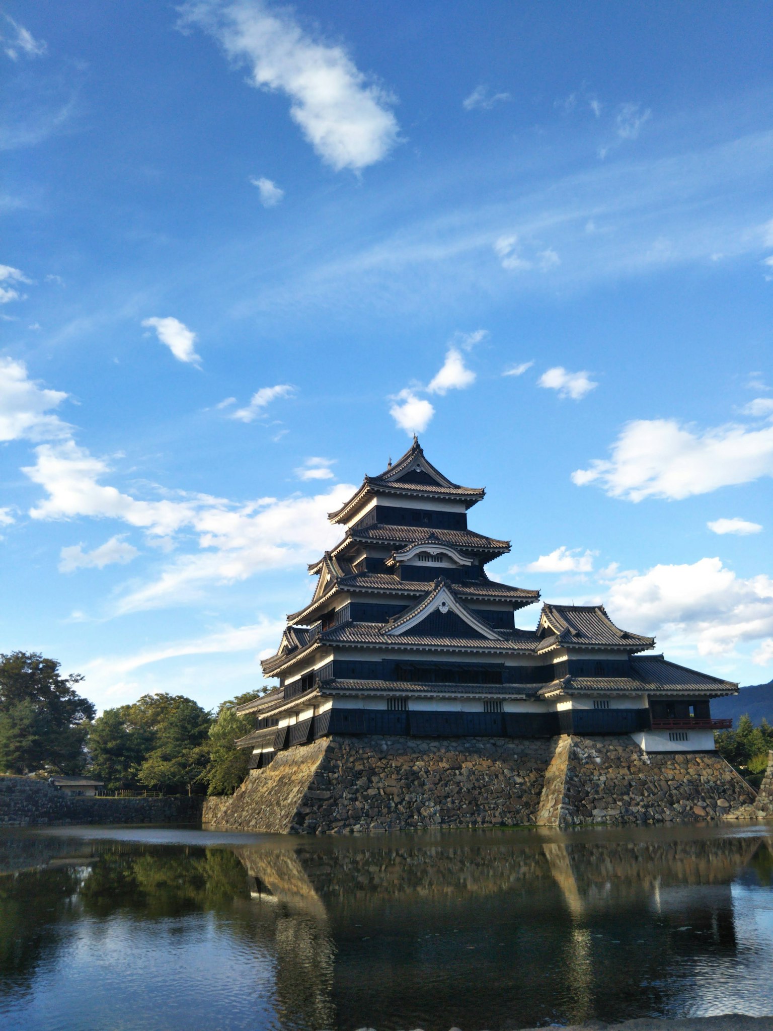 Kastil Matsumoto dengan pemandangan indah dan refleksi di bawah langit biru