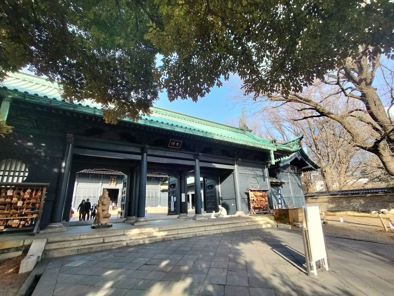 Entrée d'un temple japonais traditionnel avec un toit vert et de grands arbres