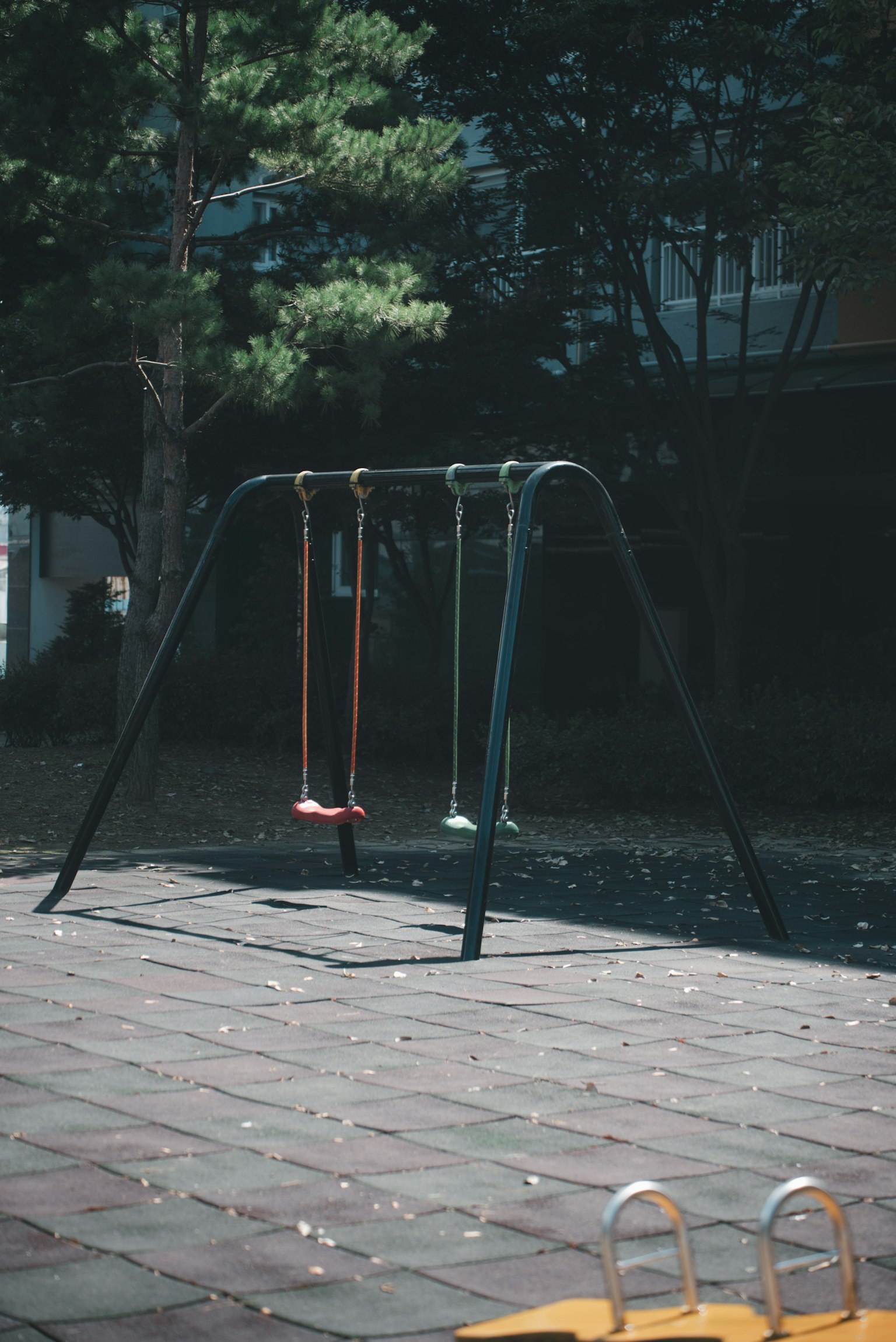 遊び場のブランコがある風景 ブランコは赤と緑の色合いで設置されている