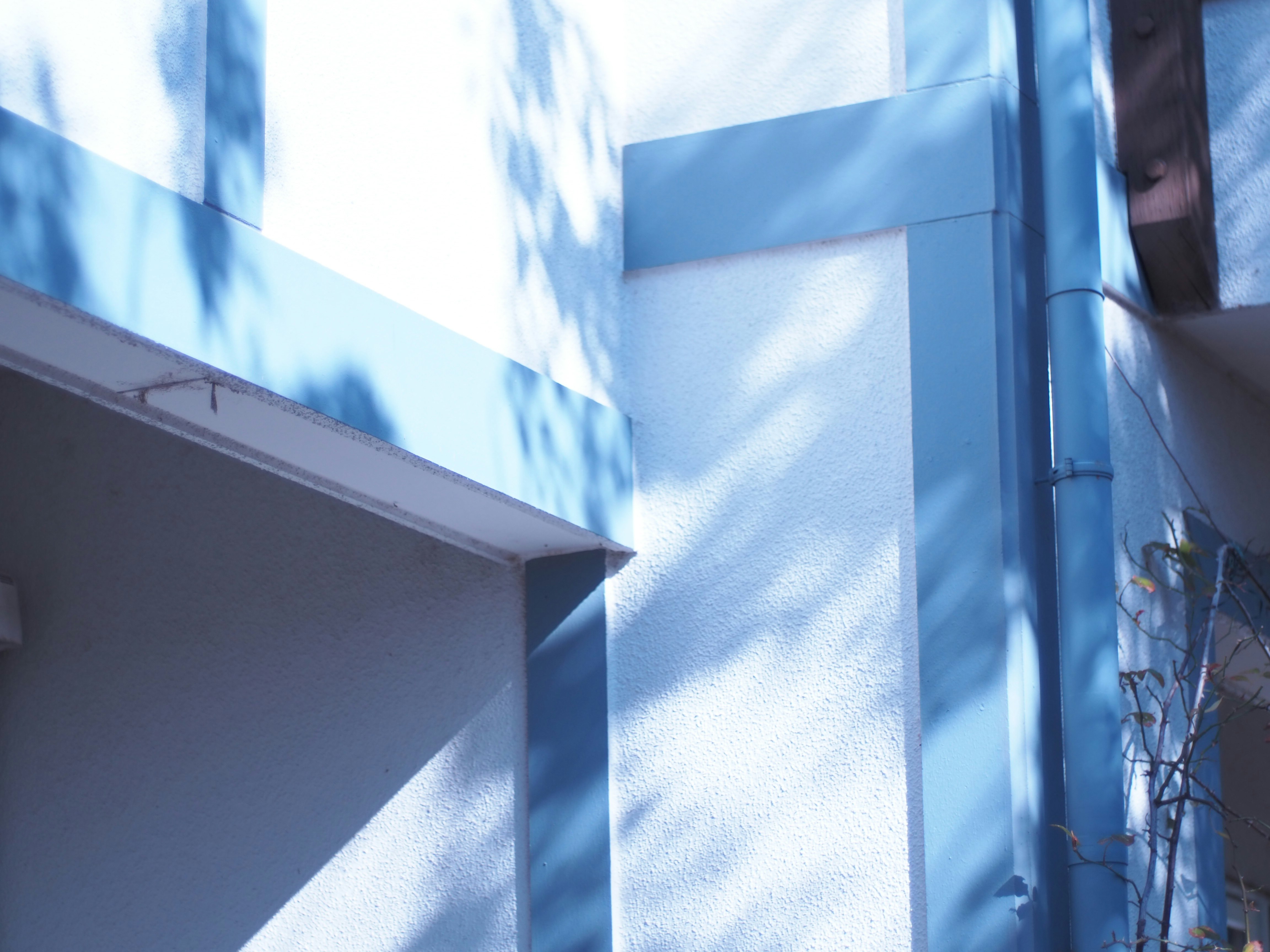 blue fabric-like flag draped over a building wall with shadows