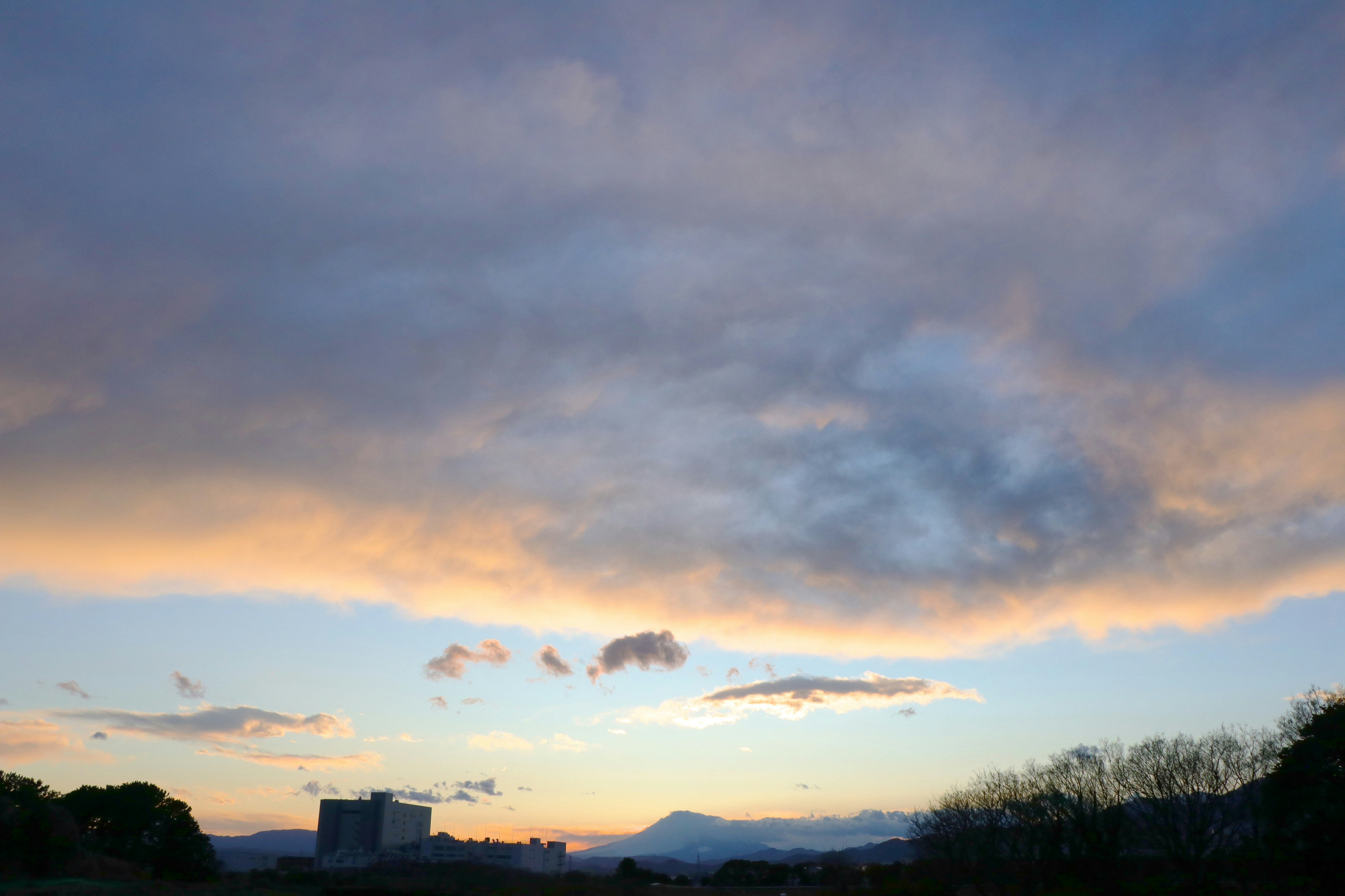 clouds over a sunset sky with distant mountain silhouettes