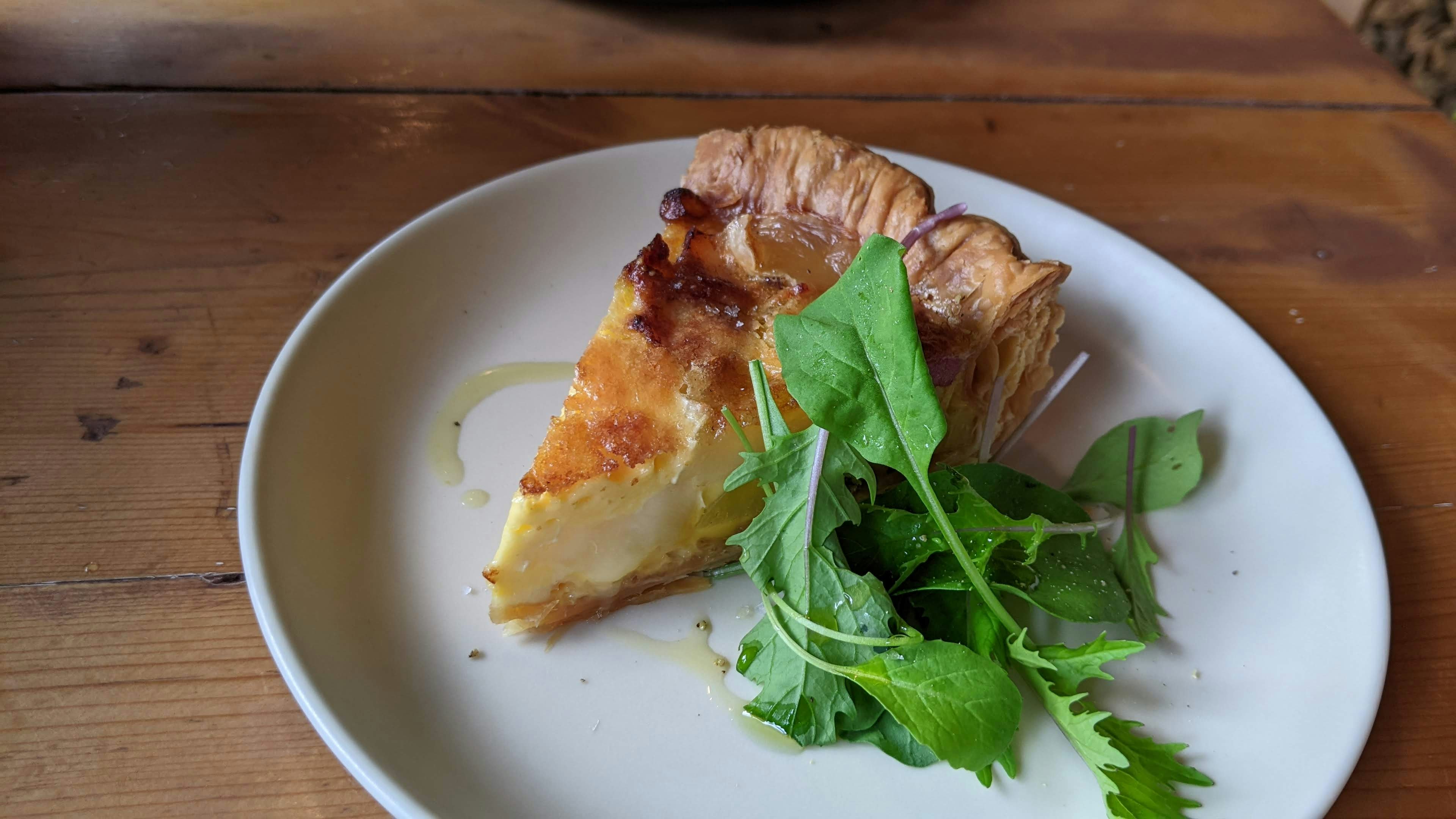 un plato de ensalada y quiche sobre una mesa de madera