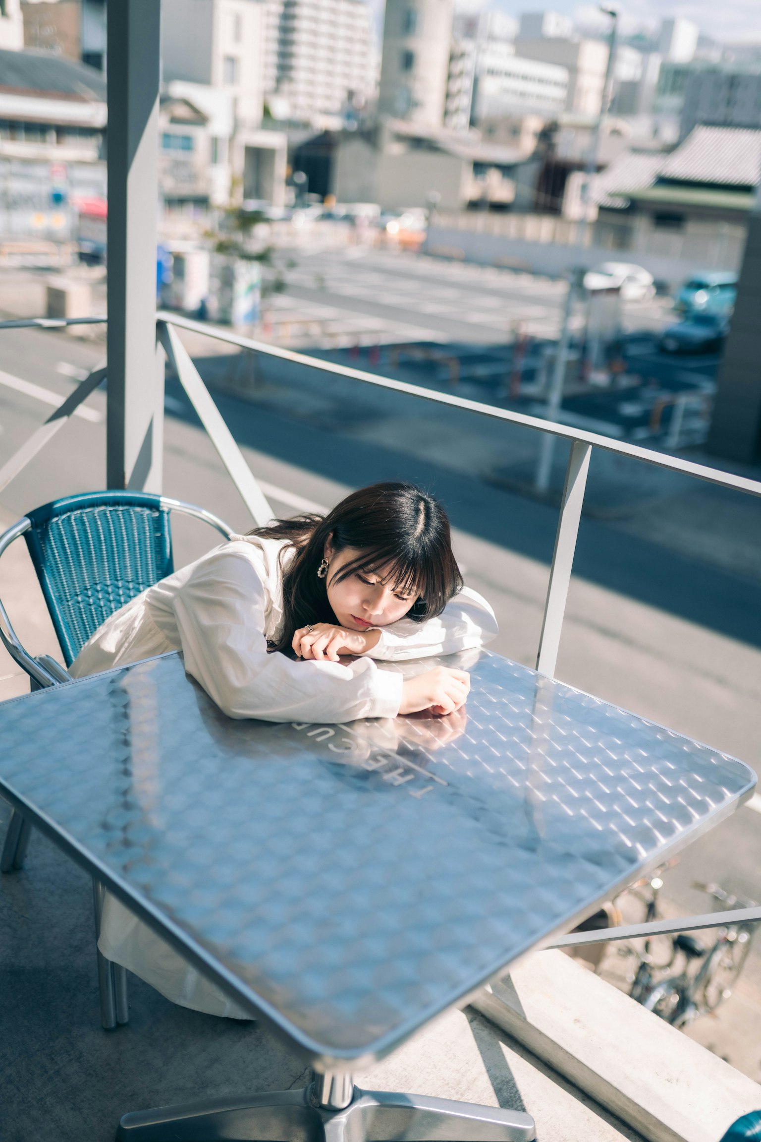 A woman leaning on a terrace table with a cityscape in the background