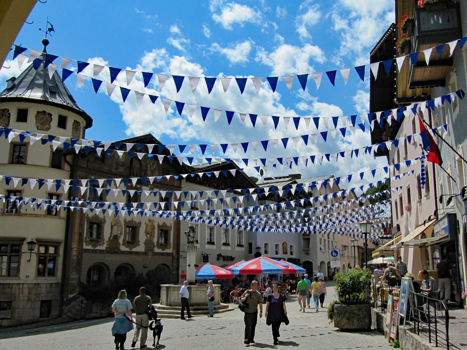 Calle decorada con banderas azules y blancas y multitudes animadas