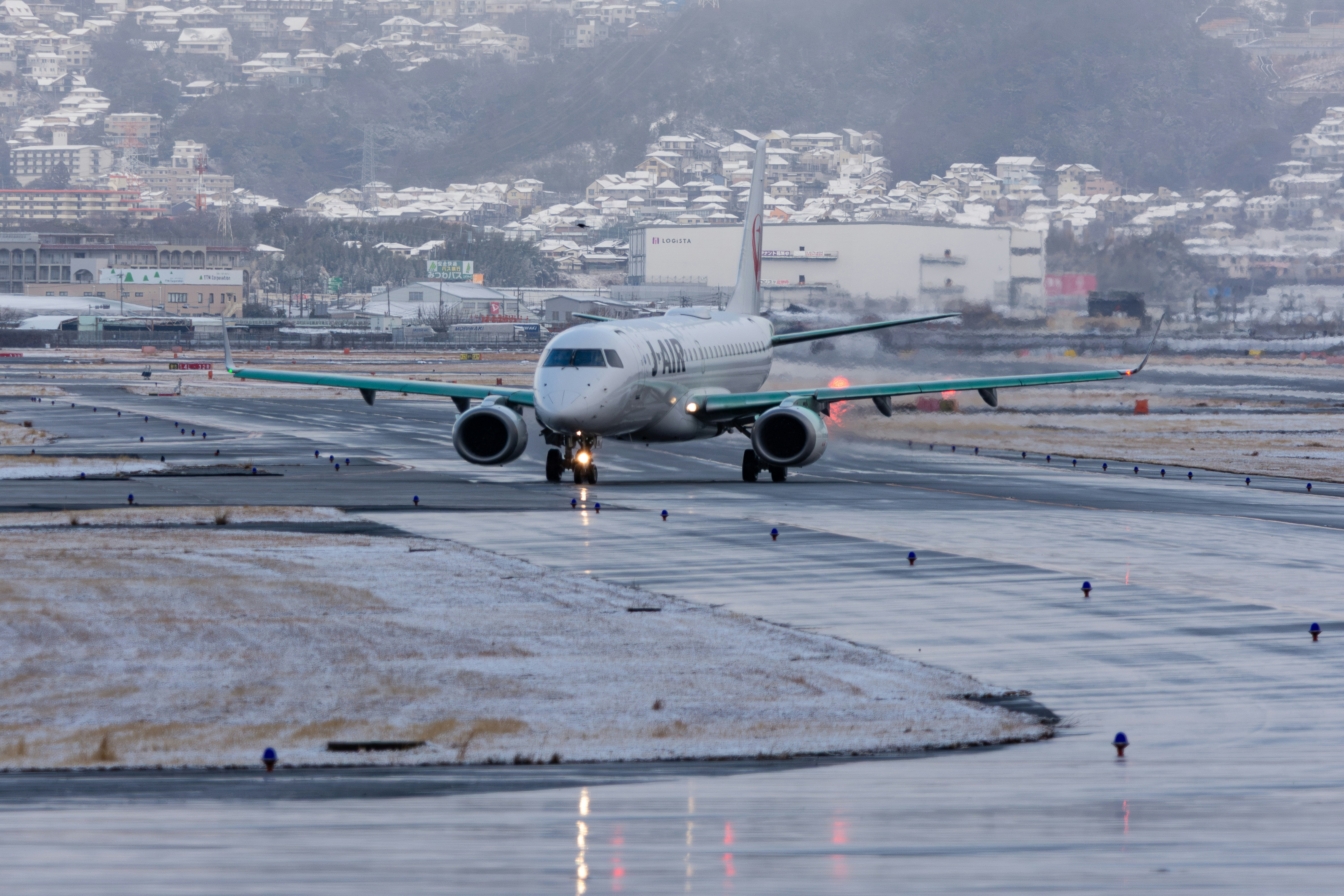 雪の伊丹空港で滑走路を進む飛行機