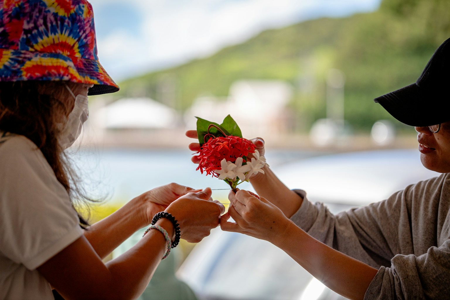 二人の女性が花のブレスレットを交換している様子 美しい自然の背景