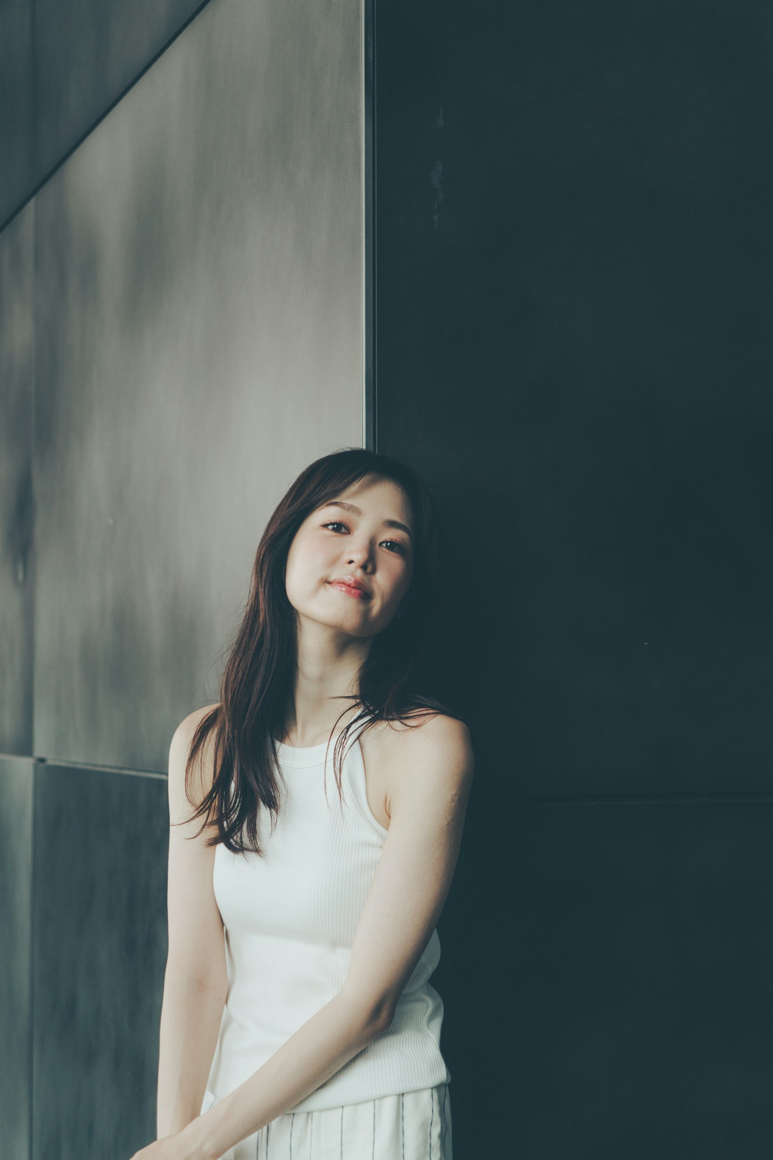 穿着白色上衣的女性靠在墙上