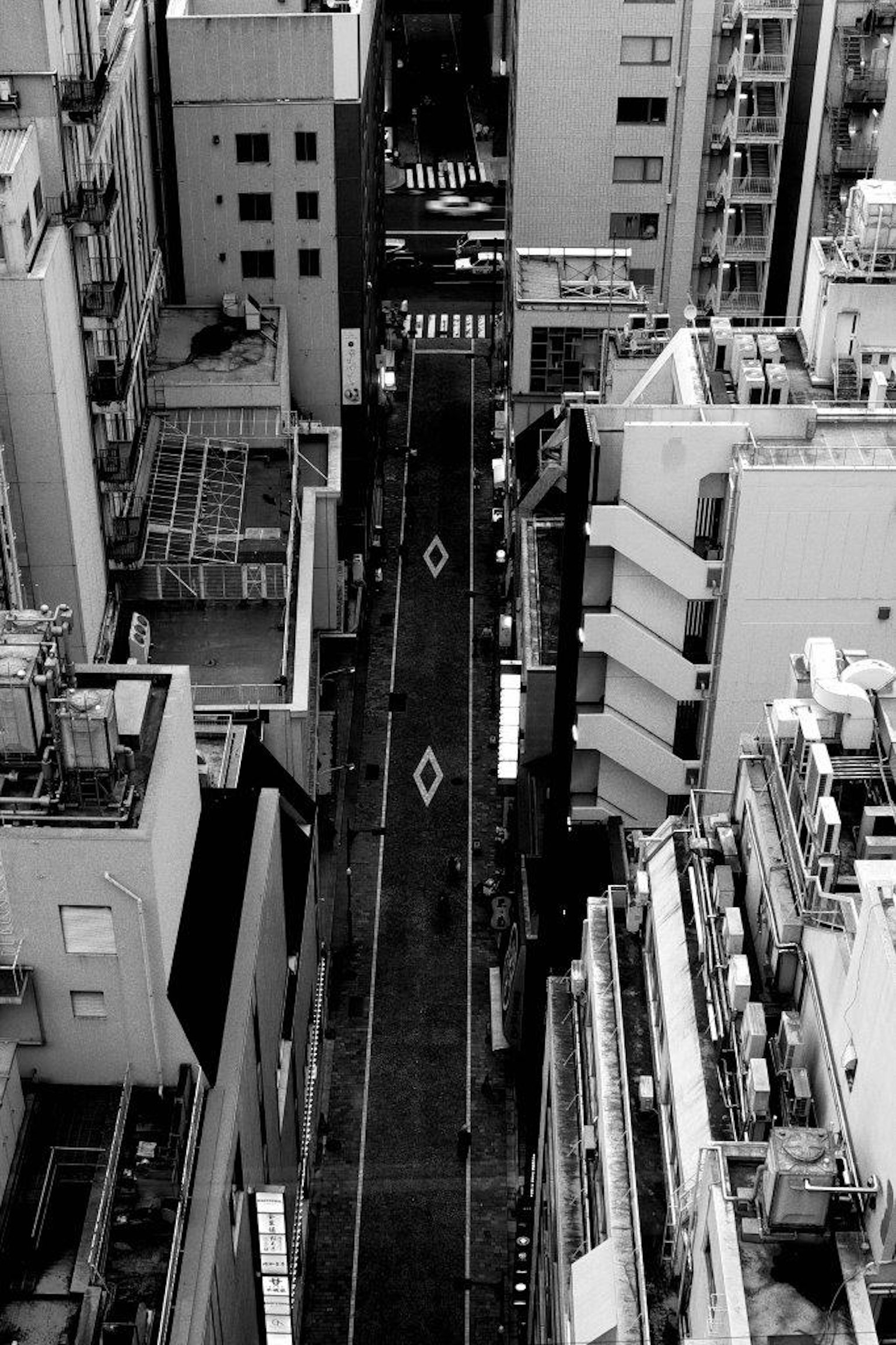 Foto in bianco e nero di una strada stretta vista tra alti edifici