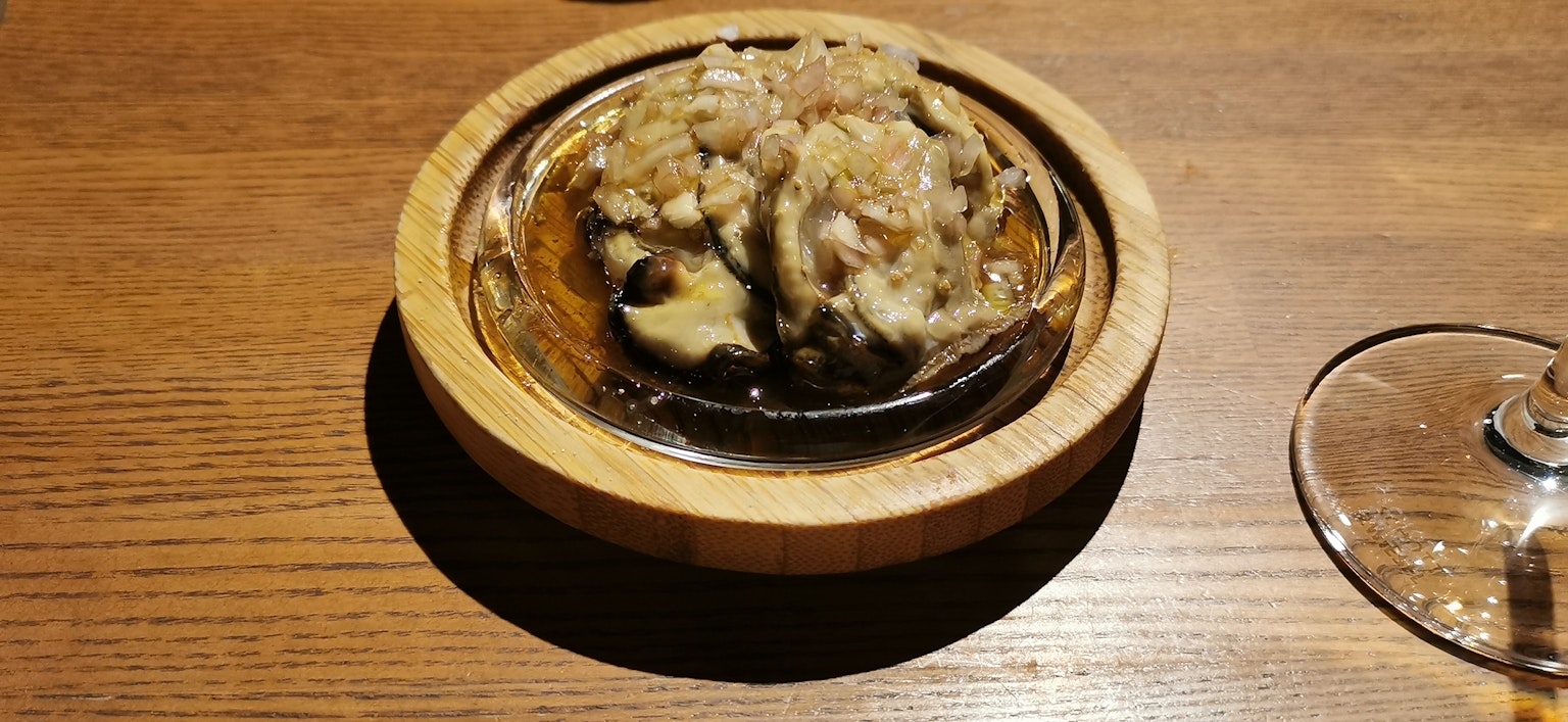 Piatto gourmet servito su un piatto di legno con un bicchiere vicino