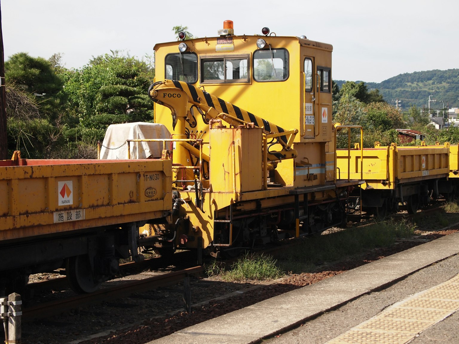 Sebuah kereta pemeliharaan kuning terparkir di rel