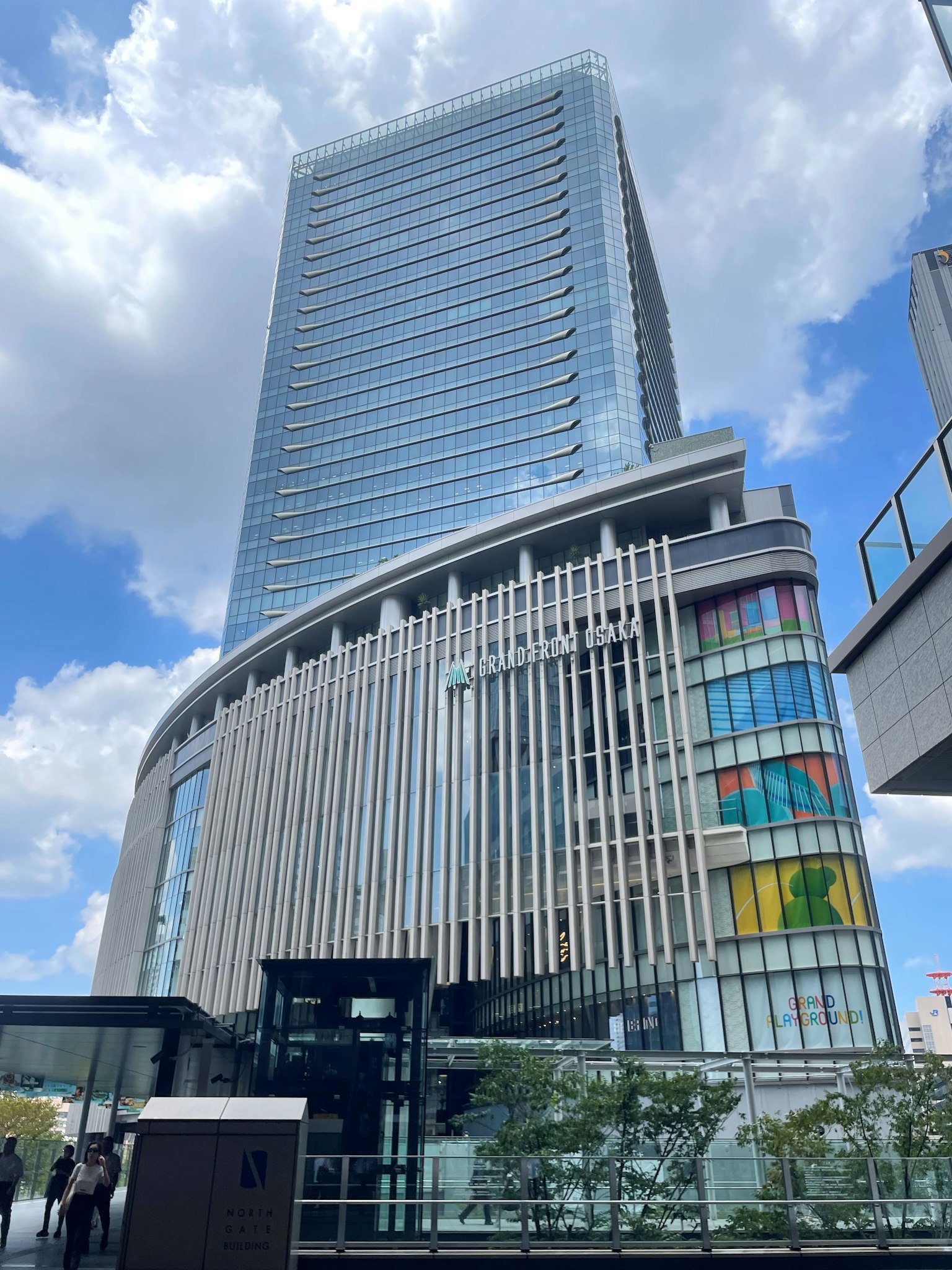 現代摩天大樓外觀，藍天白雲下的彩色玻璃展示