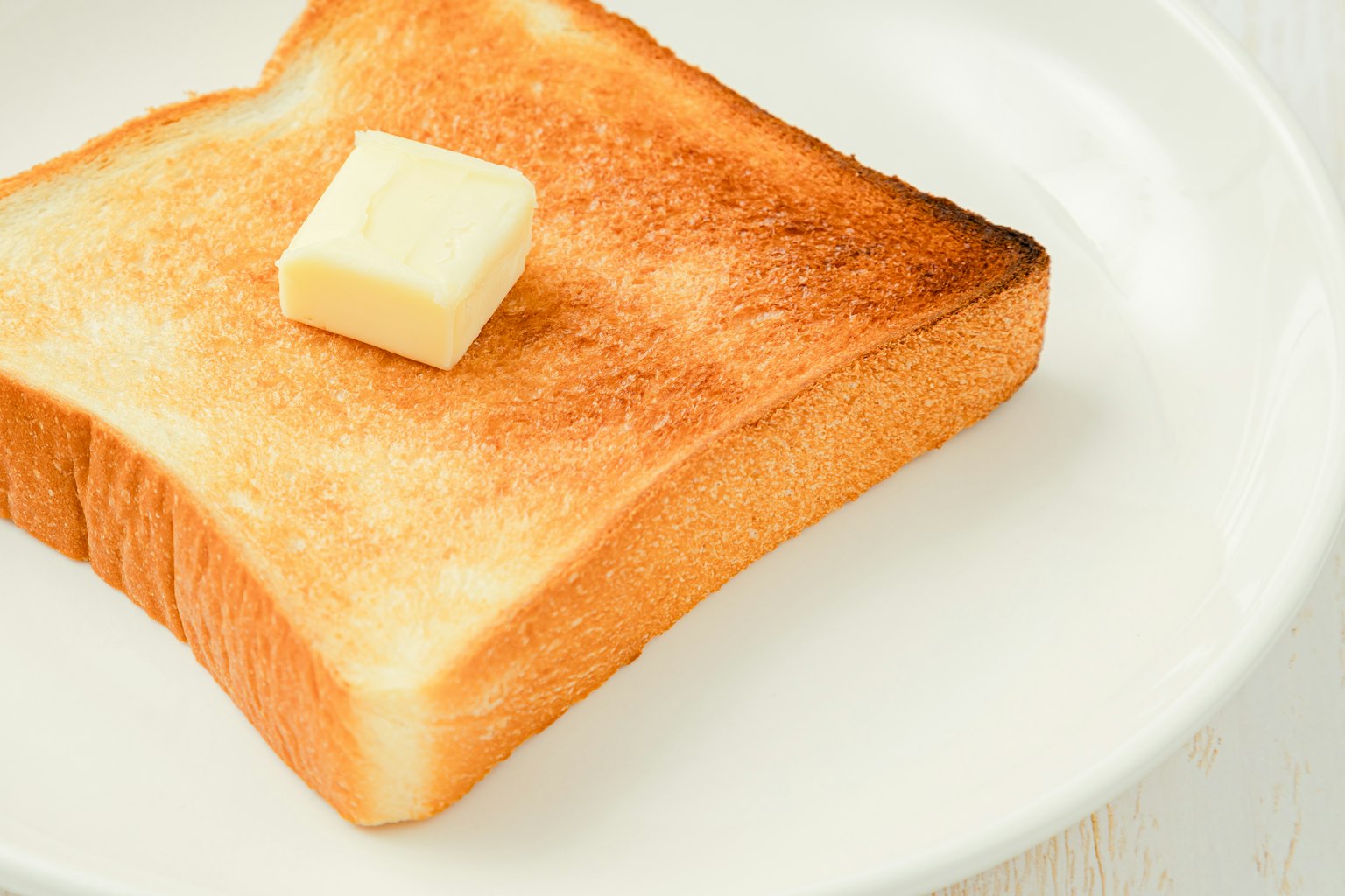Bánh mì nướng với một miếng bơ trên đĩa trắng