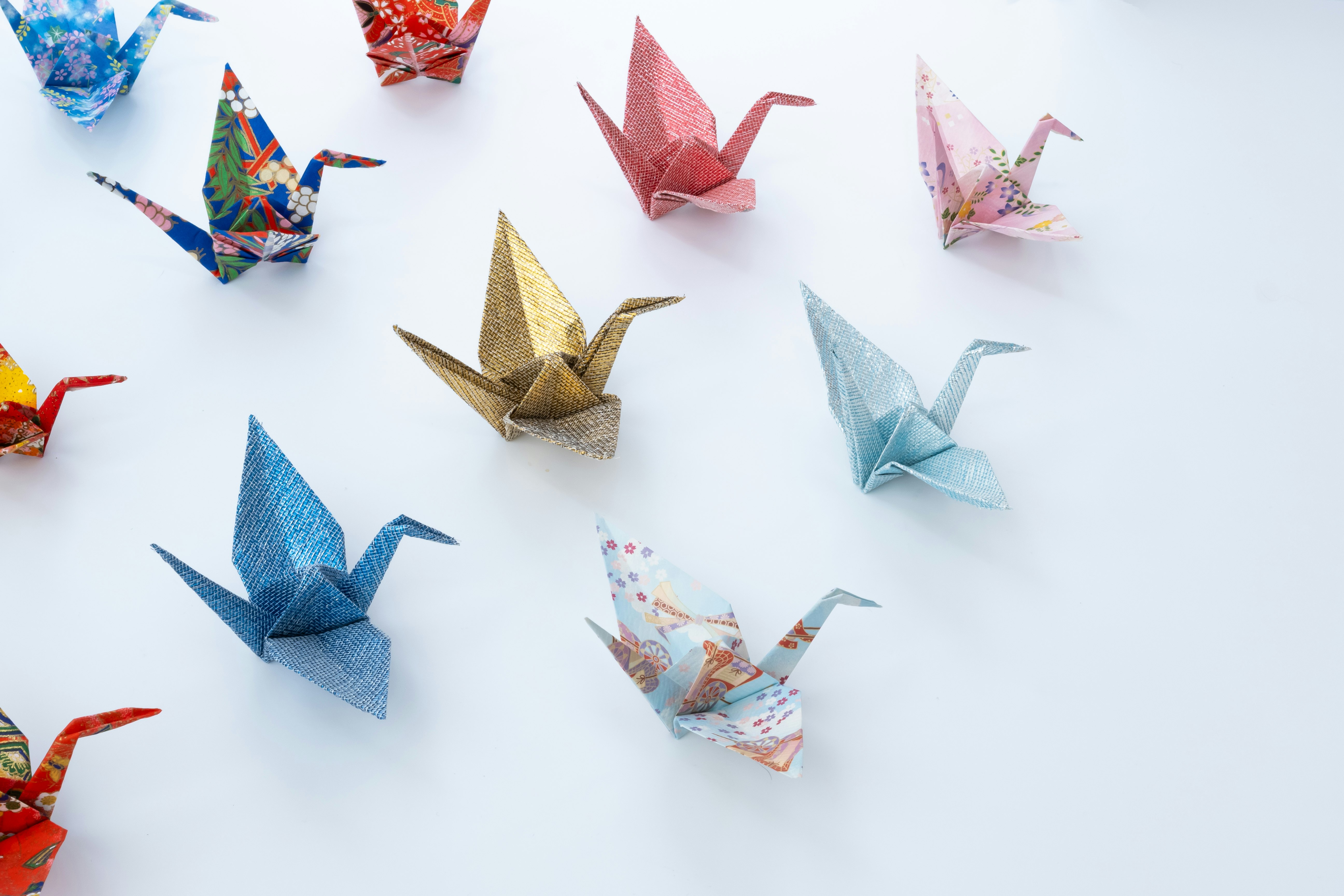 折り紙の鶴が並ぶ白い背景の上の小さな作品