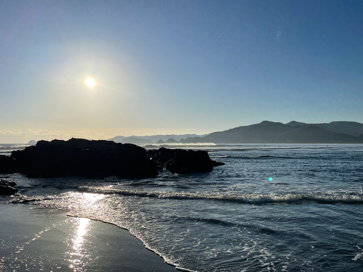 Escena costera con el sol brillando sobre las rocas y olas suaves