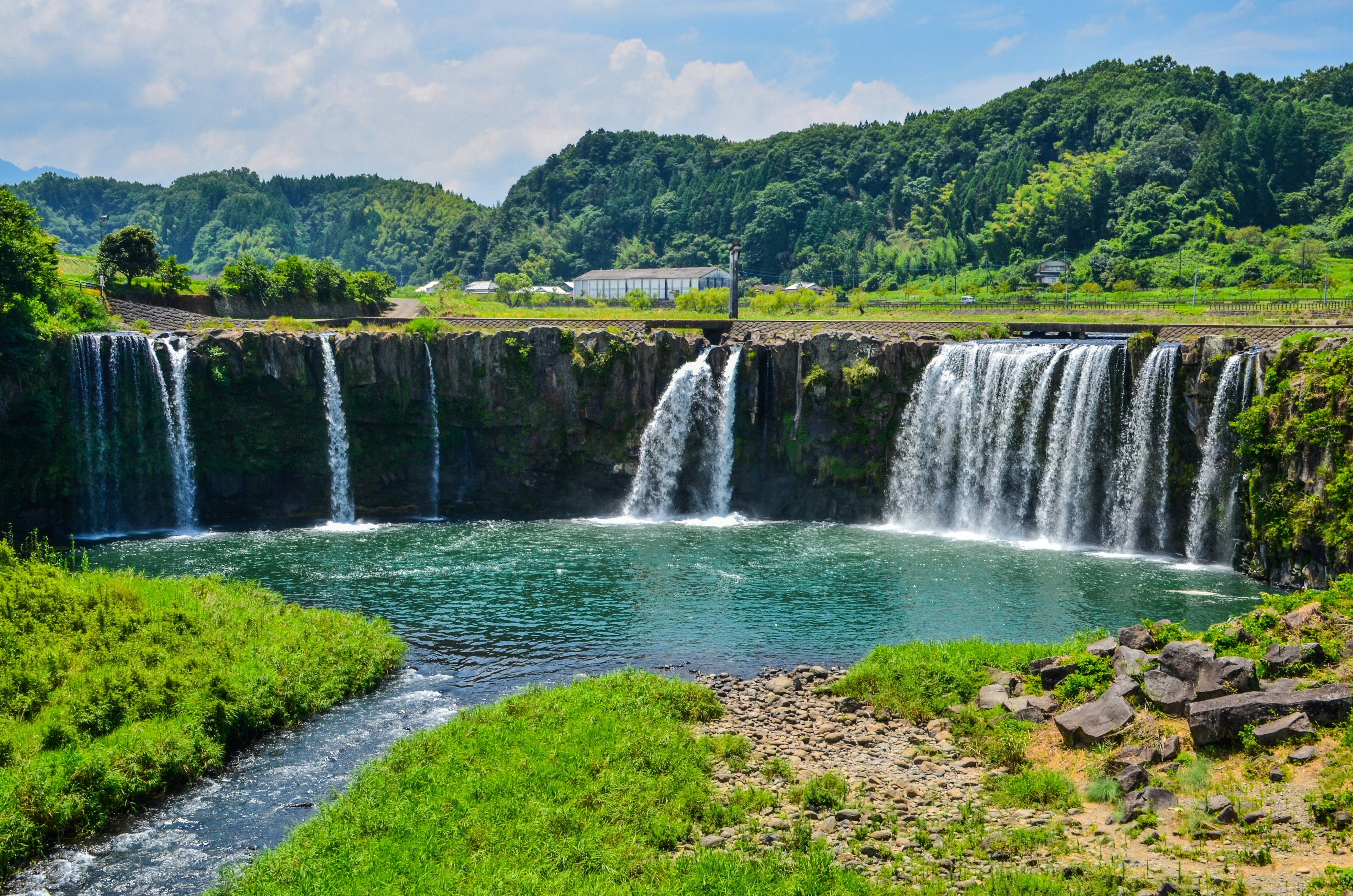 緑の川辺と滝が流れ落ちる渓谷の風景
