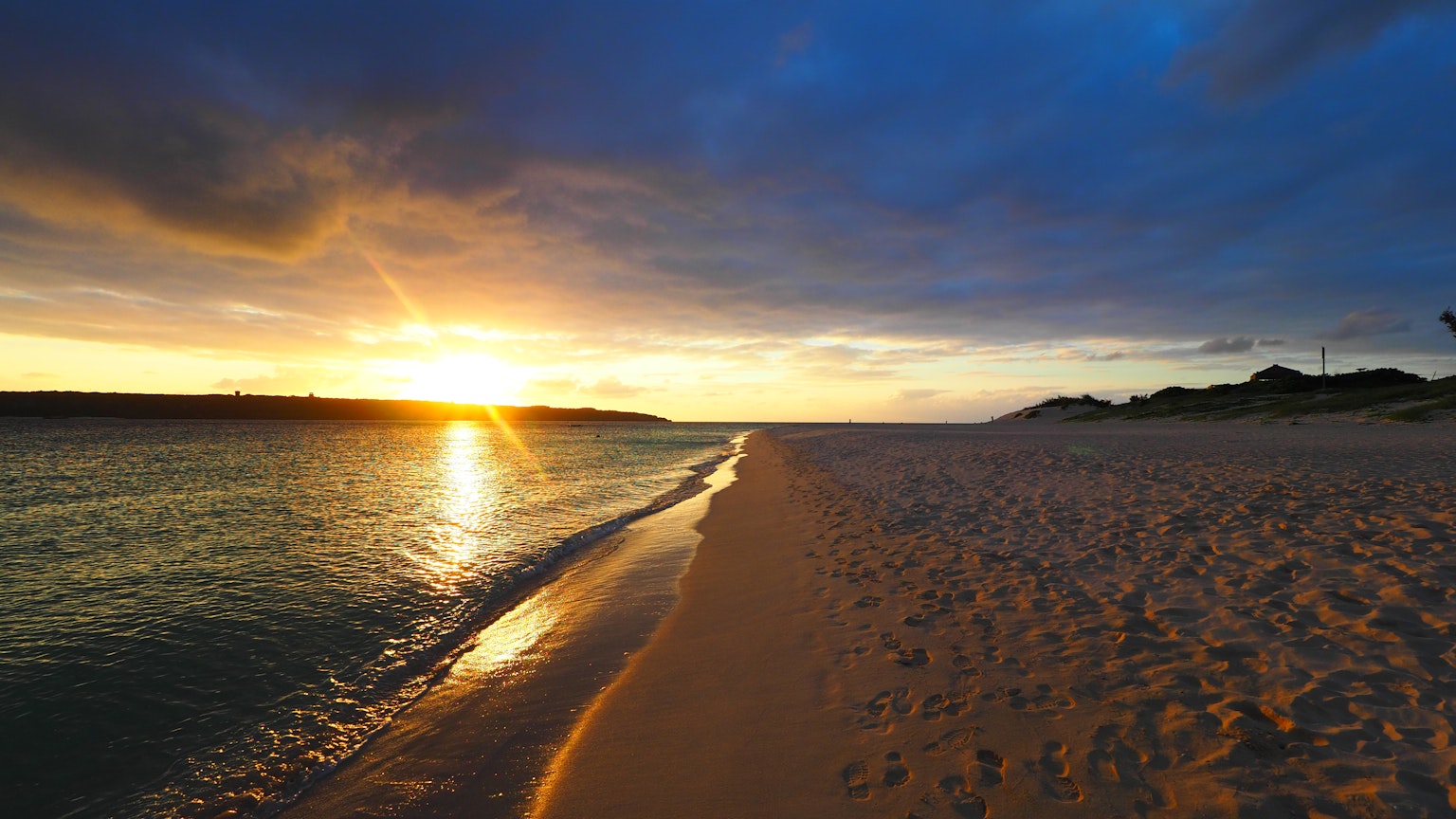 Hermoso atardecer en la playa con mar tranquilo y arena