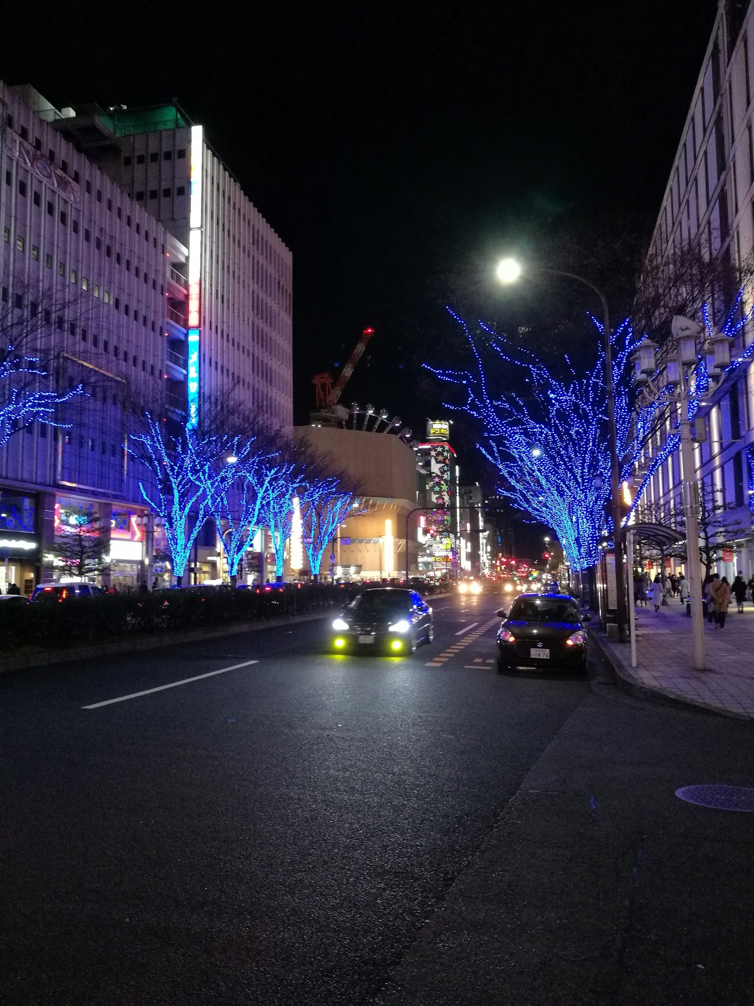 夜間城市景觀，藍色照明樹木和明亮的月亮