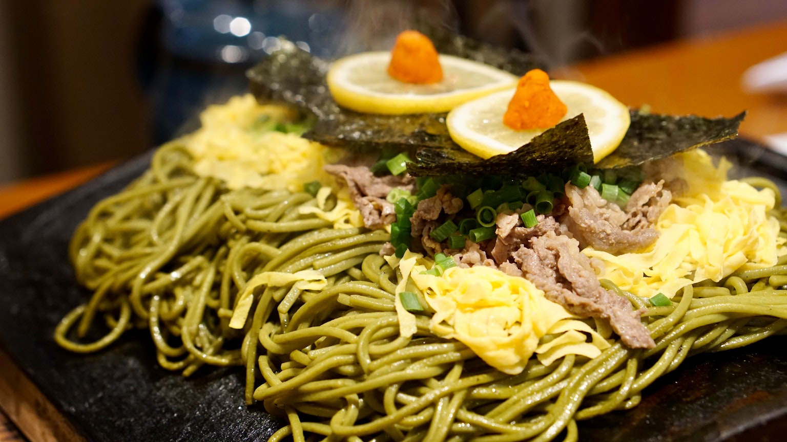 Mie hijau dengan telur dan rumput laut di atas piring panas
