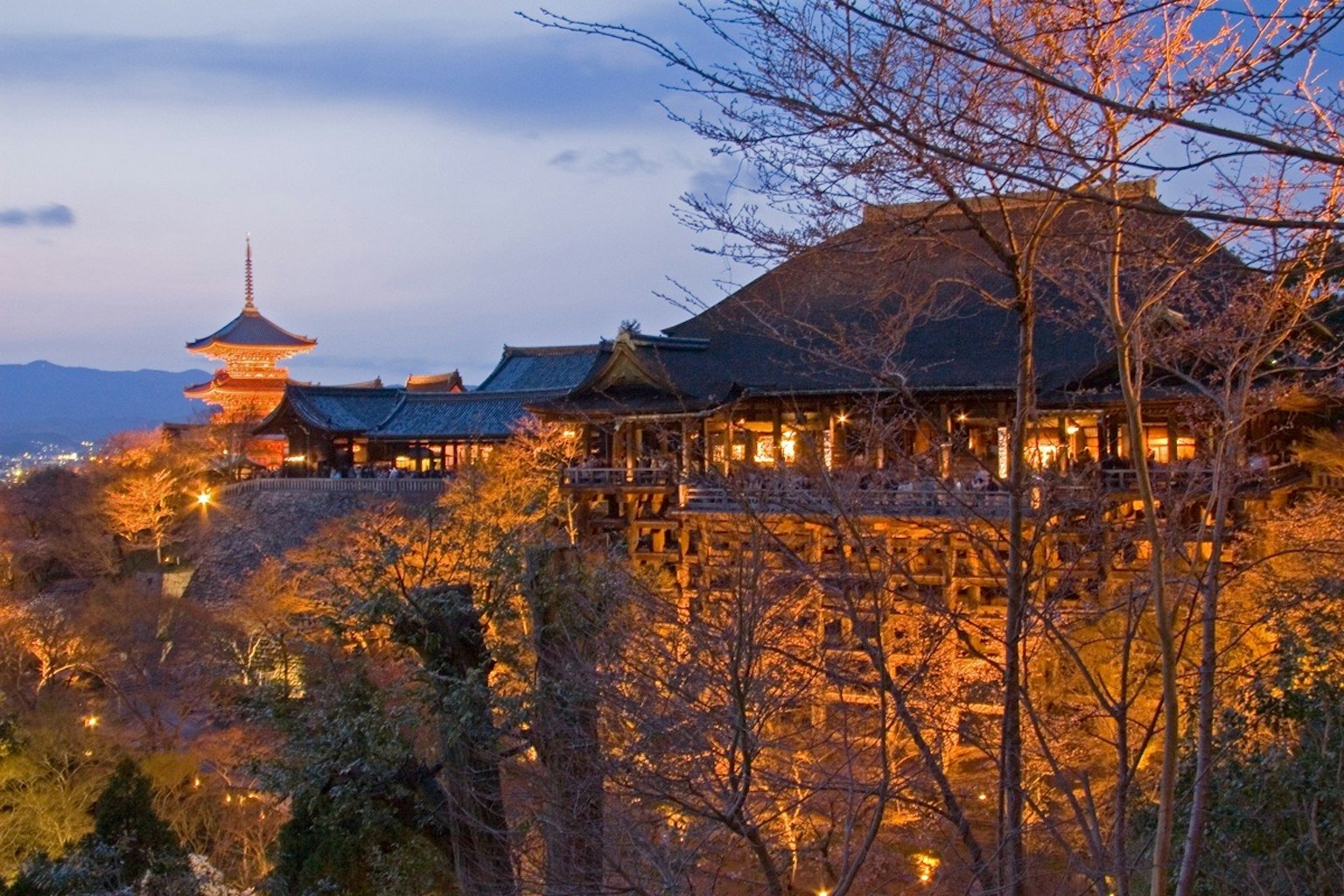 View of Kiyomizu Temple at dusk buildings illuminated in orange light