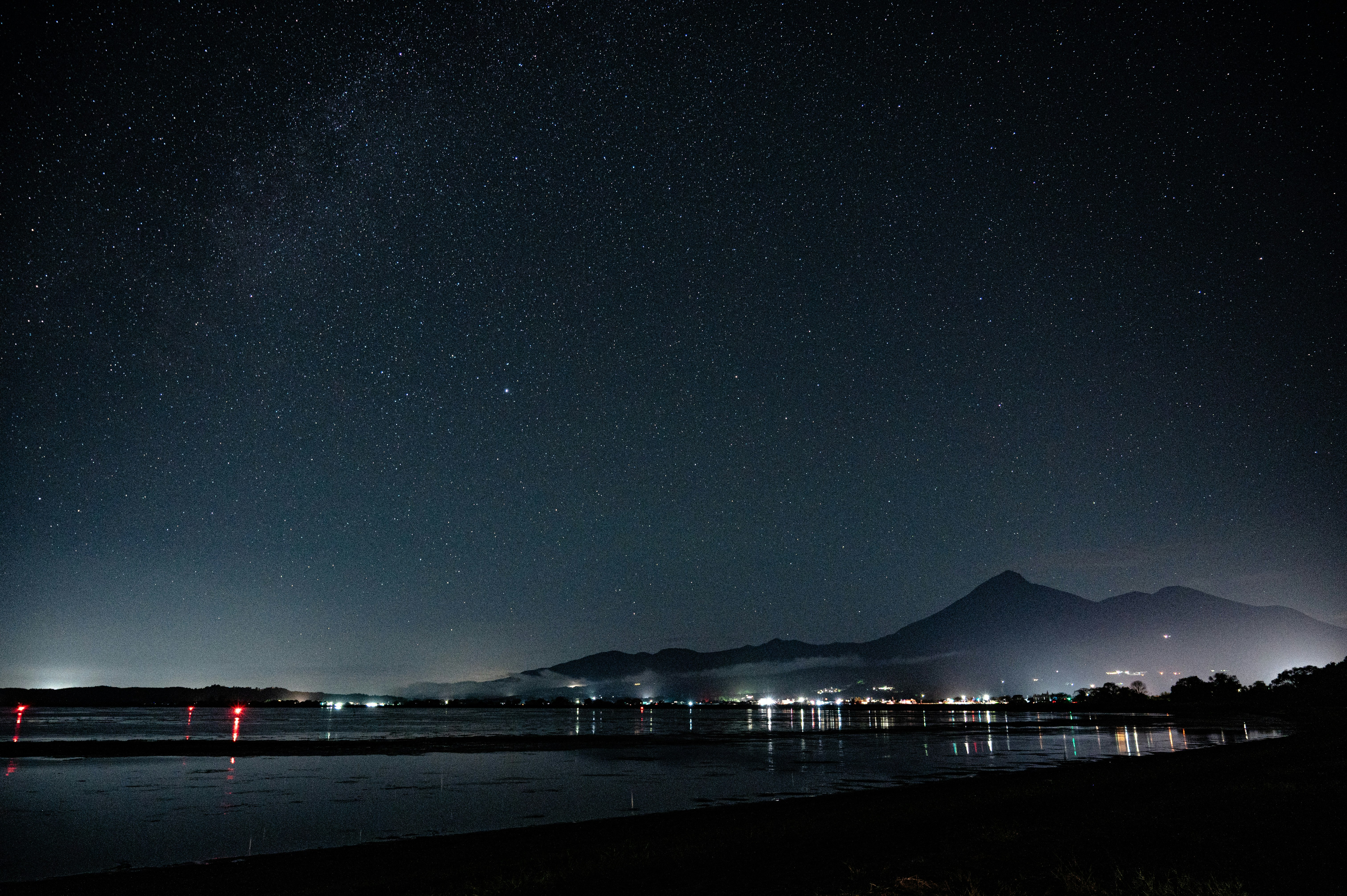 夜の海辺に浮かぶ星空と遠くの山影