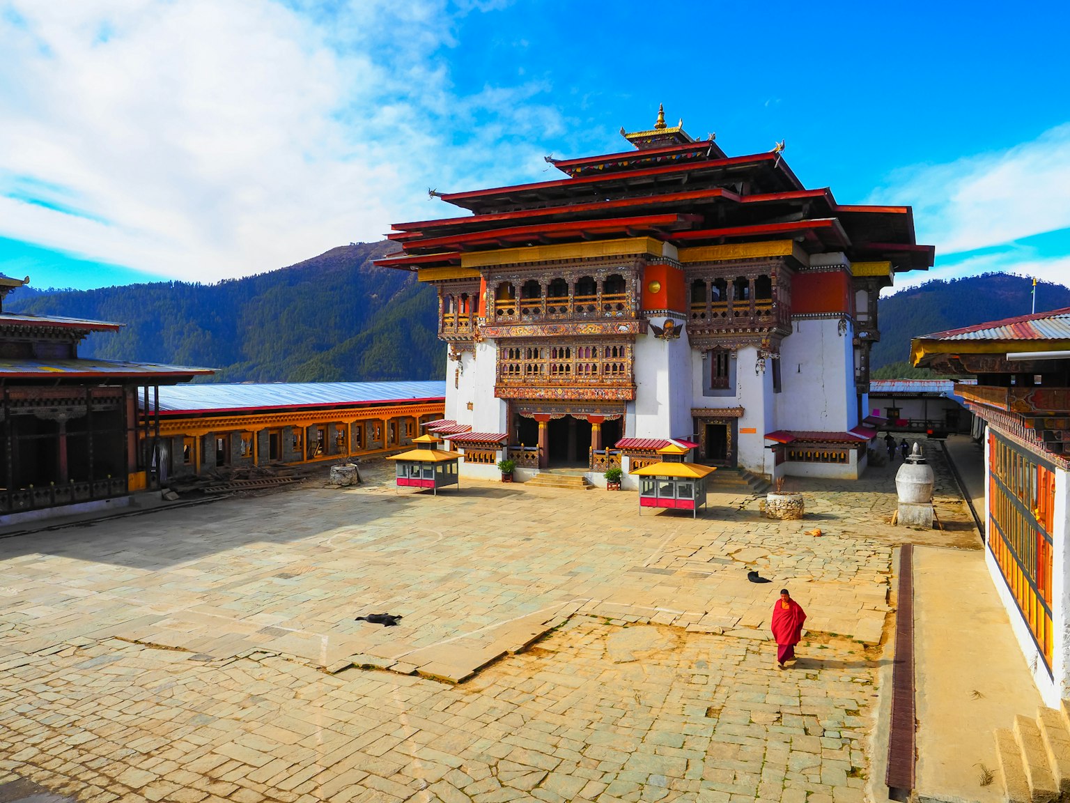 Temple bhoutanais traditionnel entouré de montagnes magnifiques avec une cour spacieuse