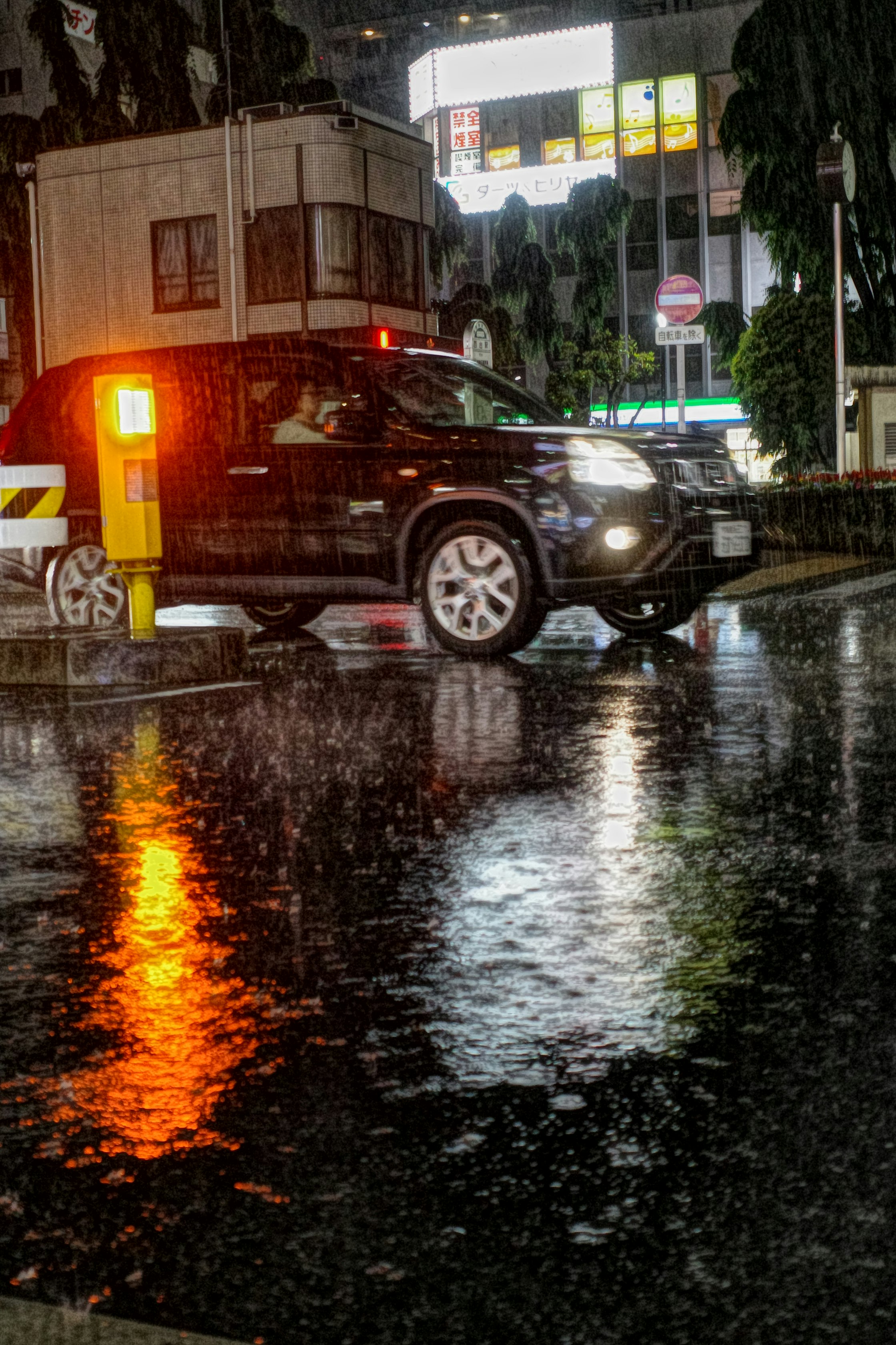雨の夜に濡れた路面を走る車のある街角