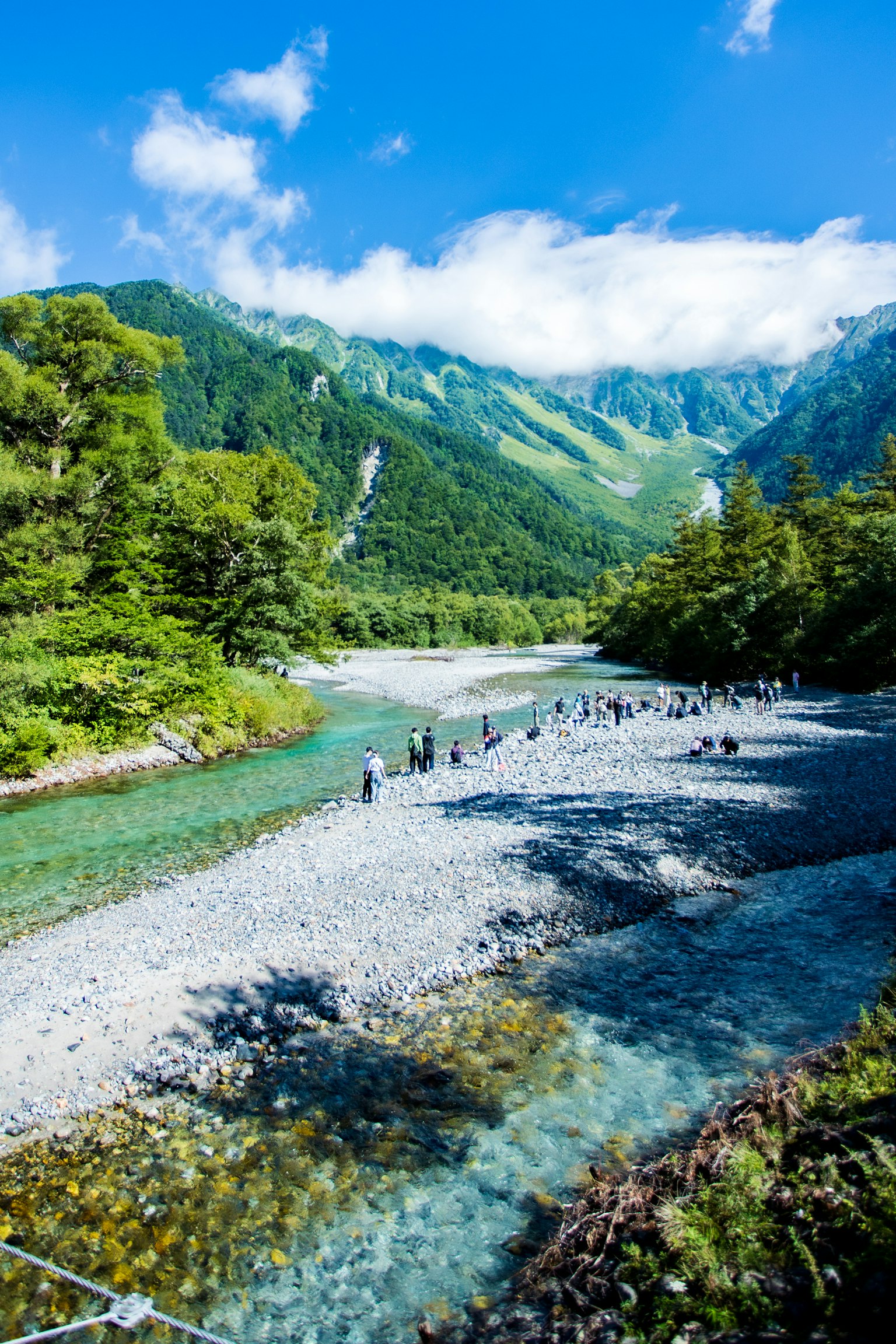 美しい山々に囲まれた清流と人々が集う風景