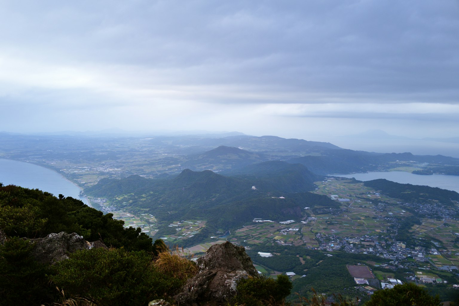 Pemandangan panorama dari puncak gunung menampilkan laut dan lanskap hijau