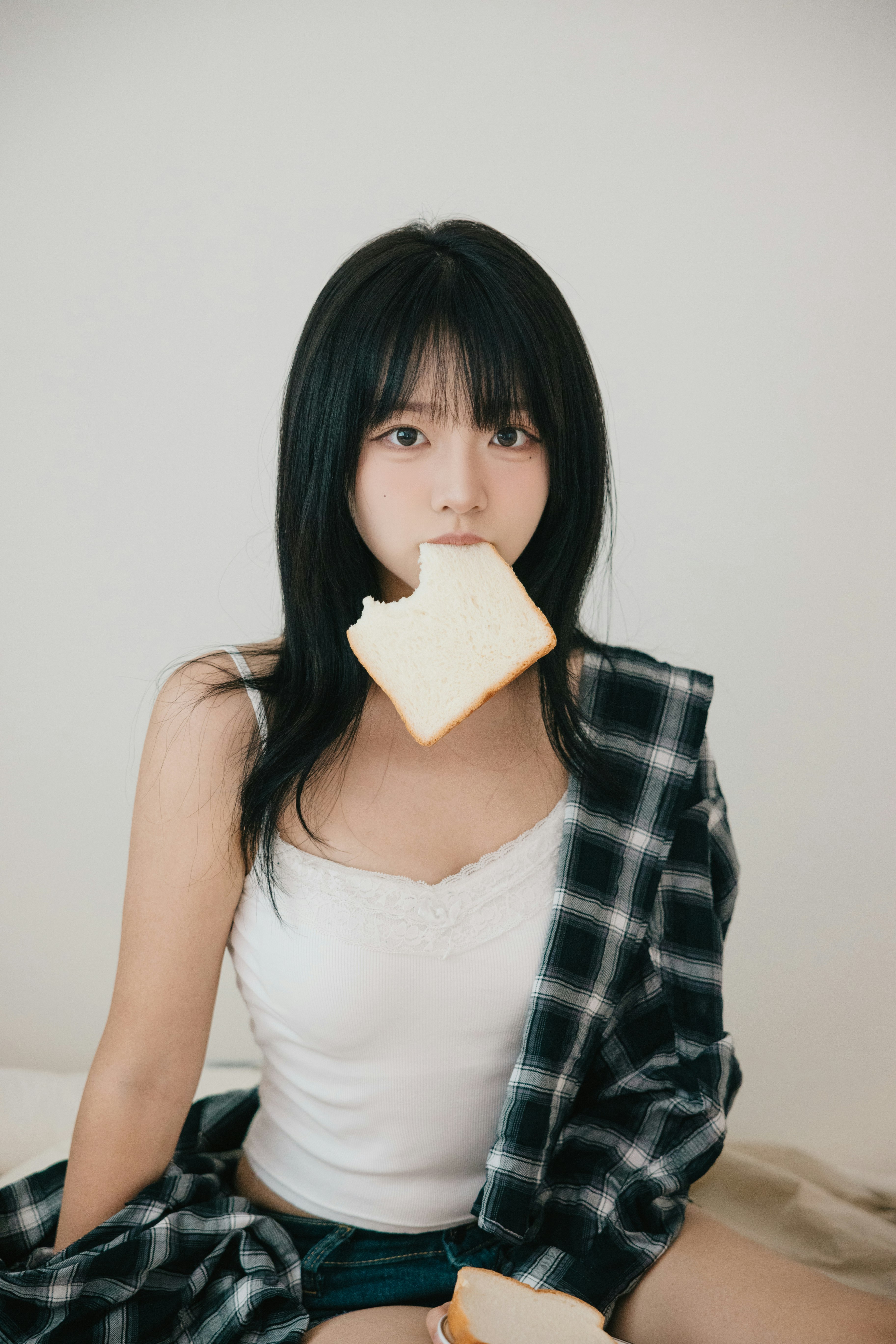 白いキャミソールの女性が頬に手を添えるポートレート