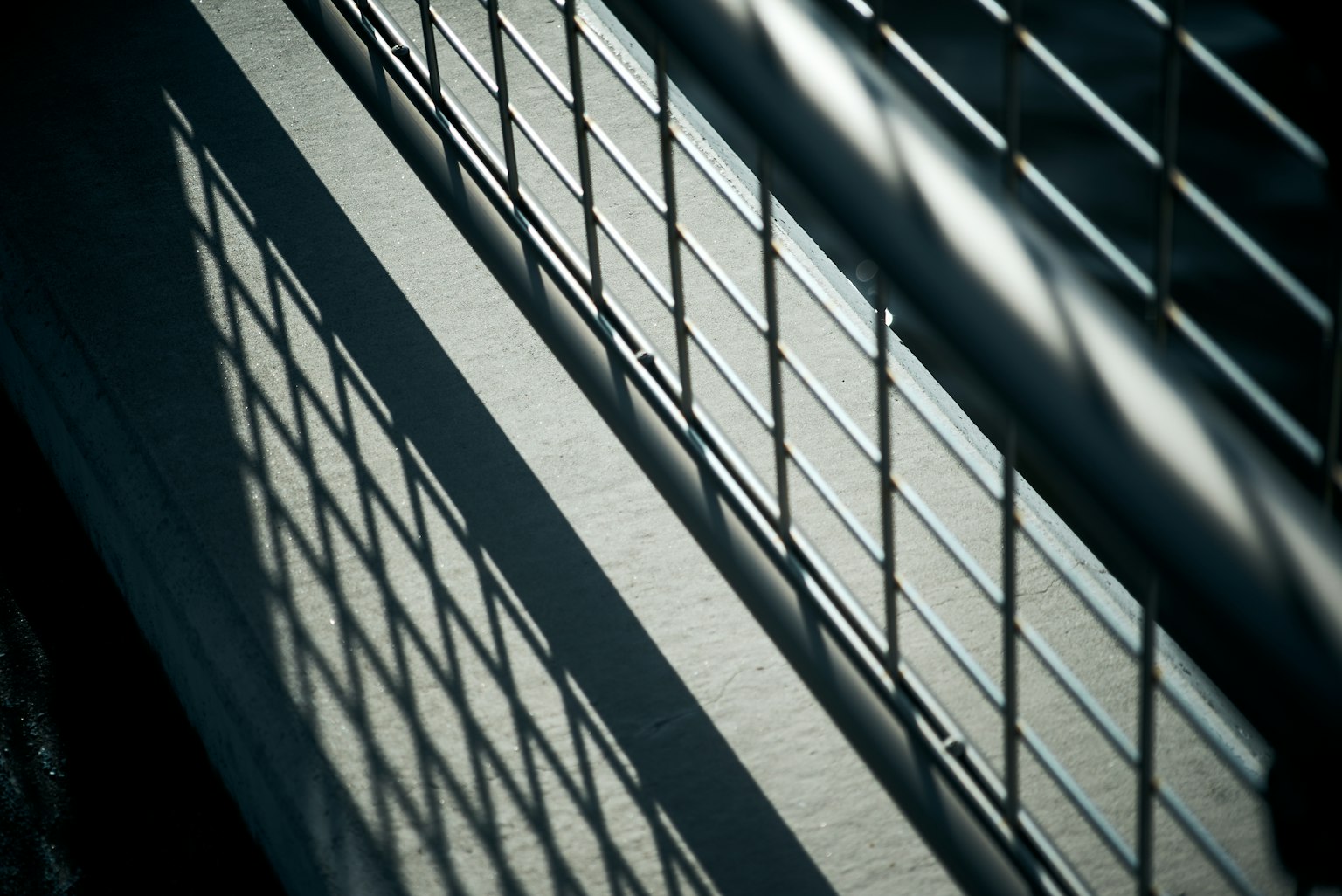 Kontrast von Licht und Schatten an einem Metallzaun