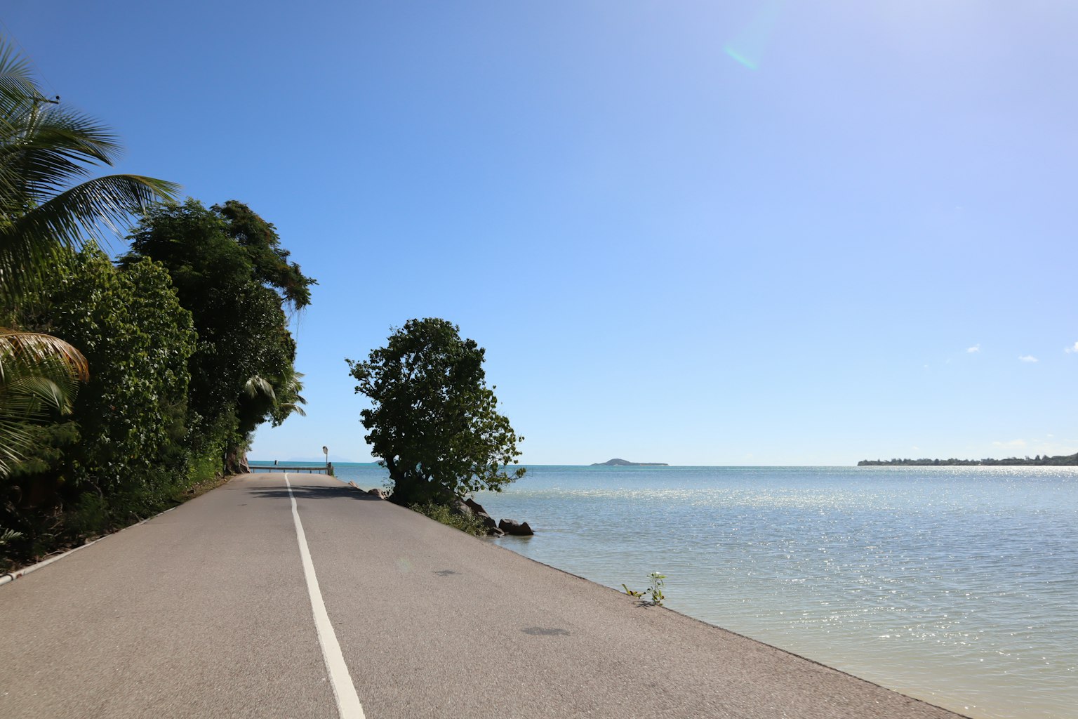 Vista escénica de una carretera junto al mar azul y el cielo