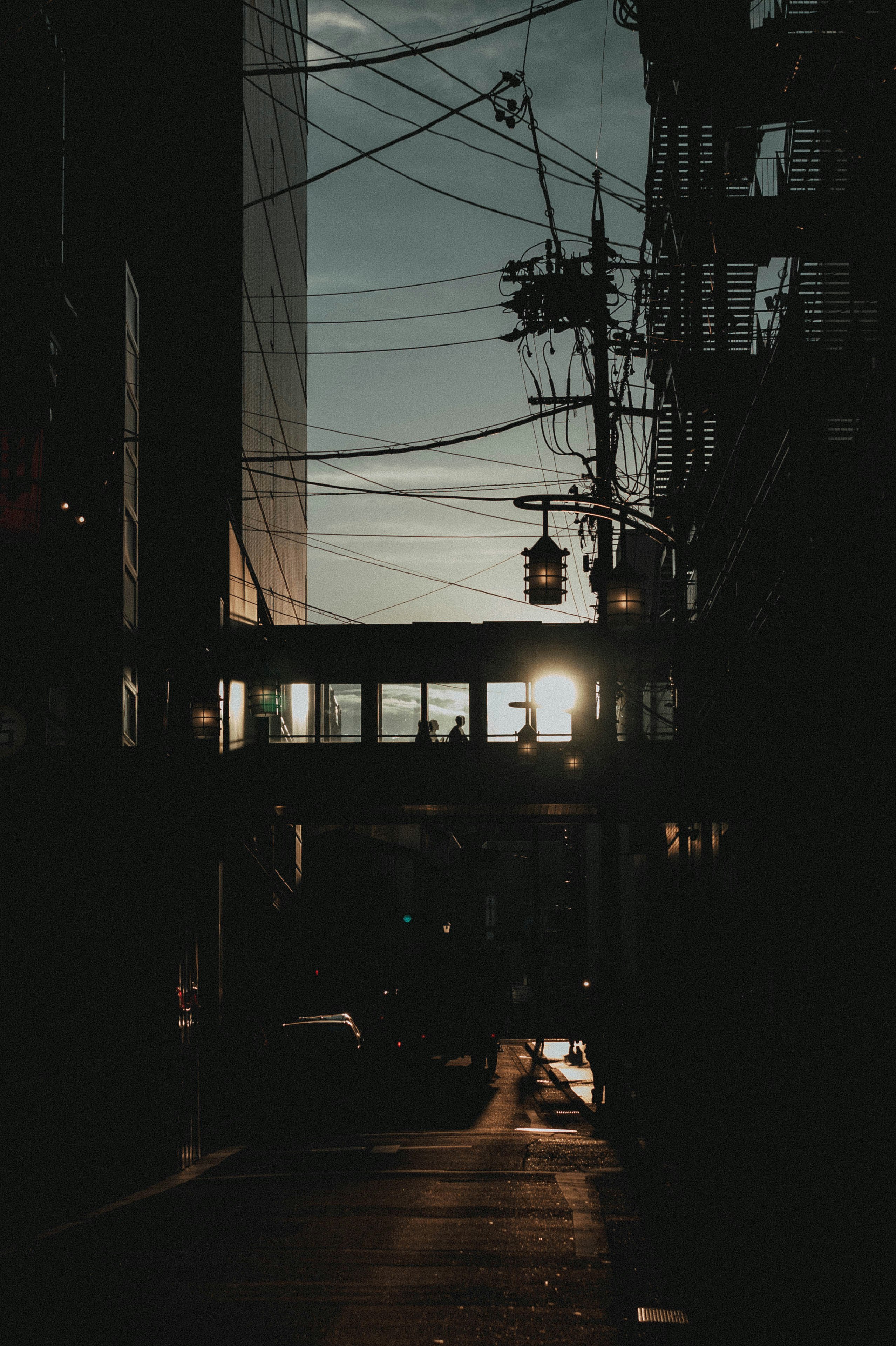 callejón nocturno con cables eléctricos y faroles al atardecer