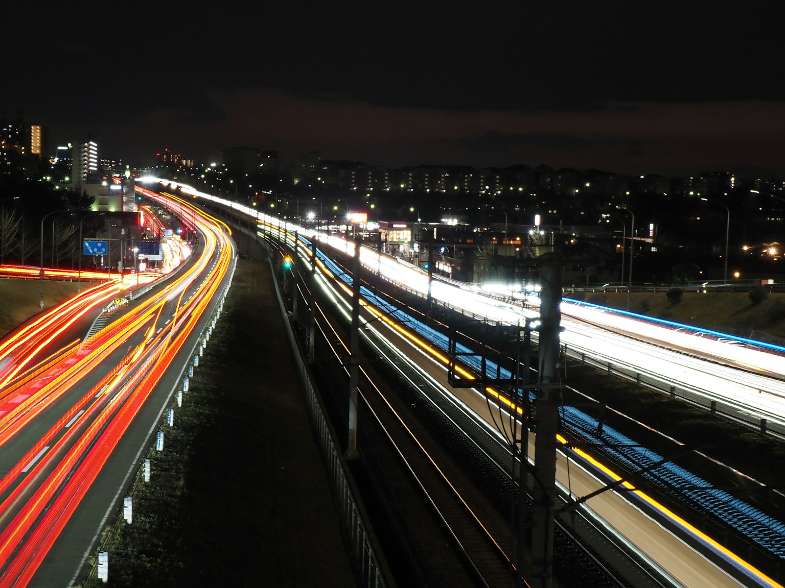 Scène nocturne d'autoroute et de chemin de fer avec des traînées lumineuses