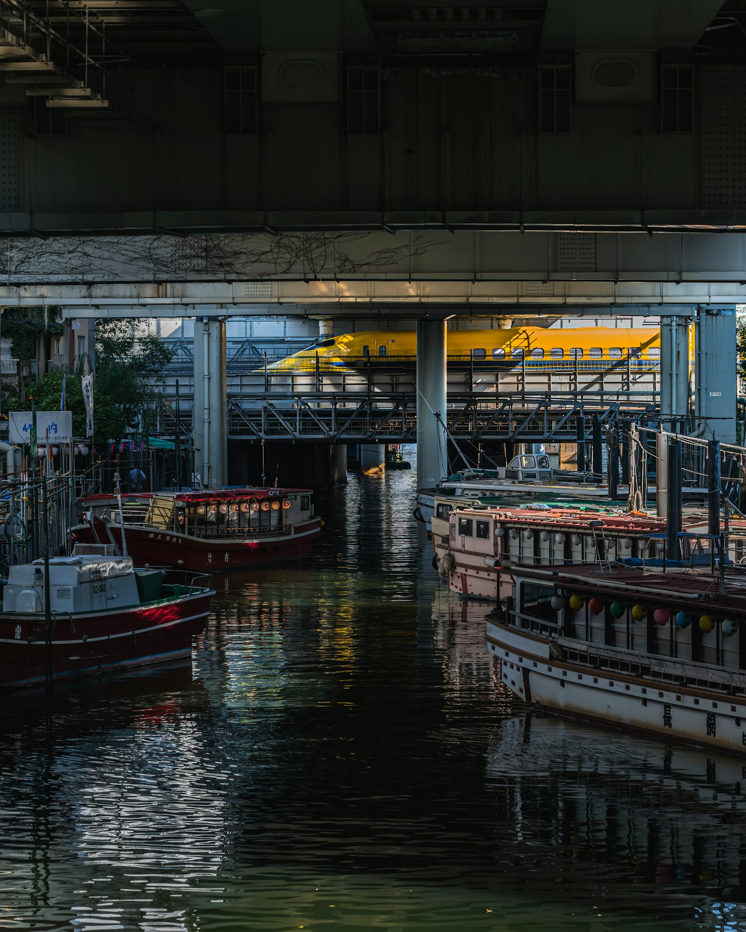Boats docked in a waterway under a bridge