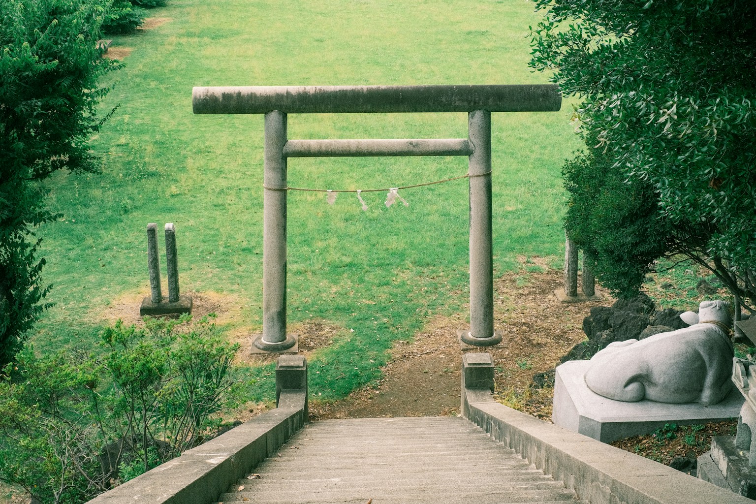 Portico in pietra con paesaggio di erba verde e statua sullo sfondo