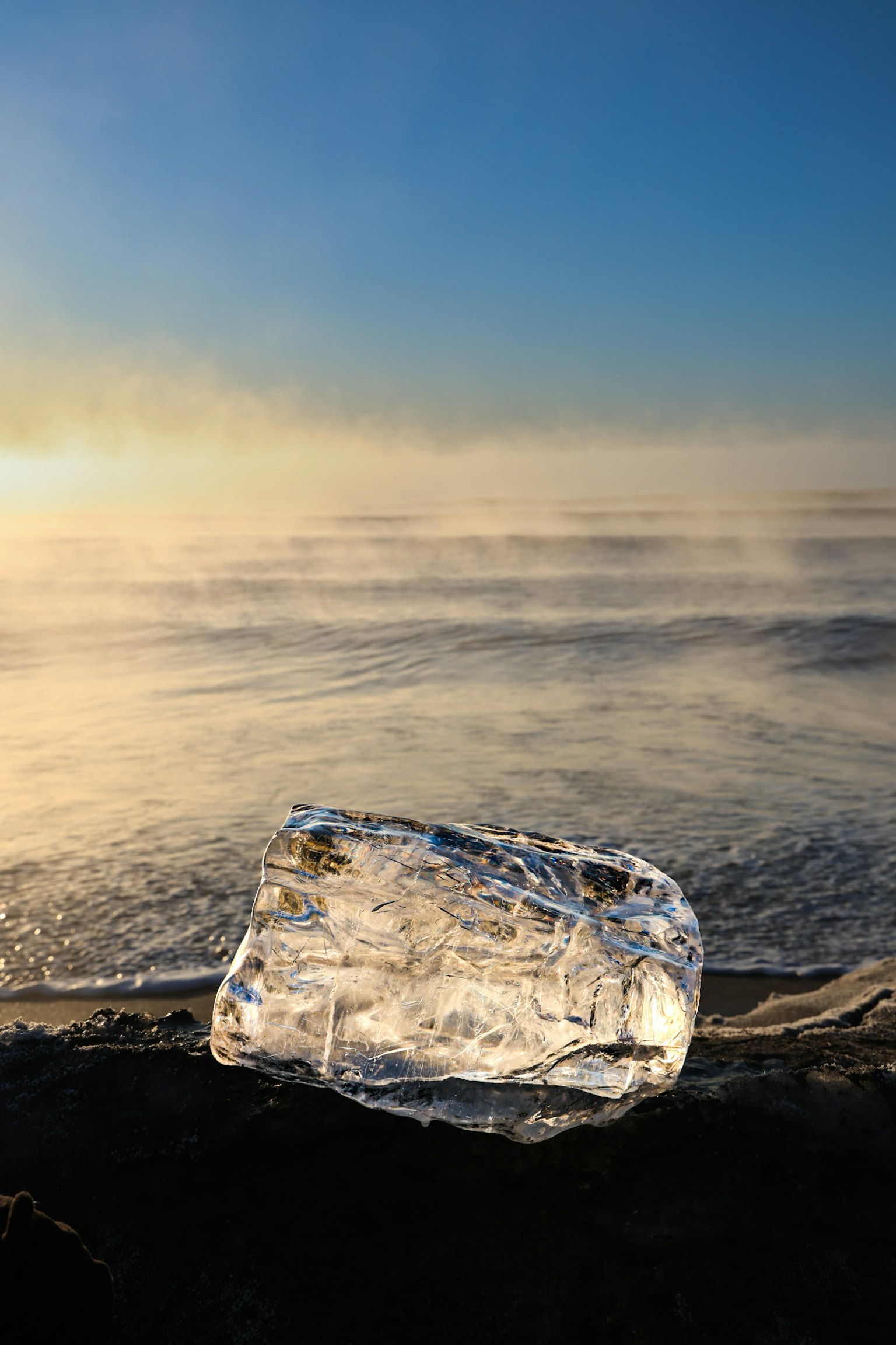 Ice block on the shore with a blue sky and misty ocean