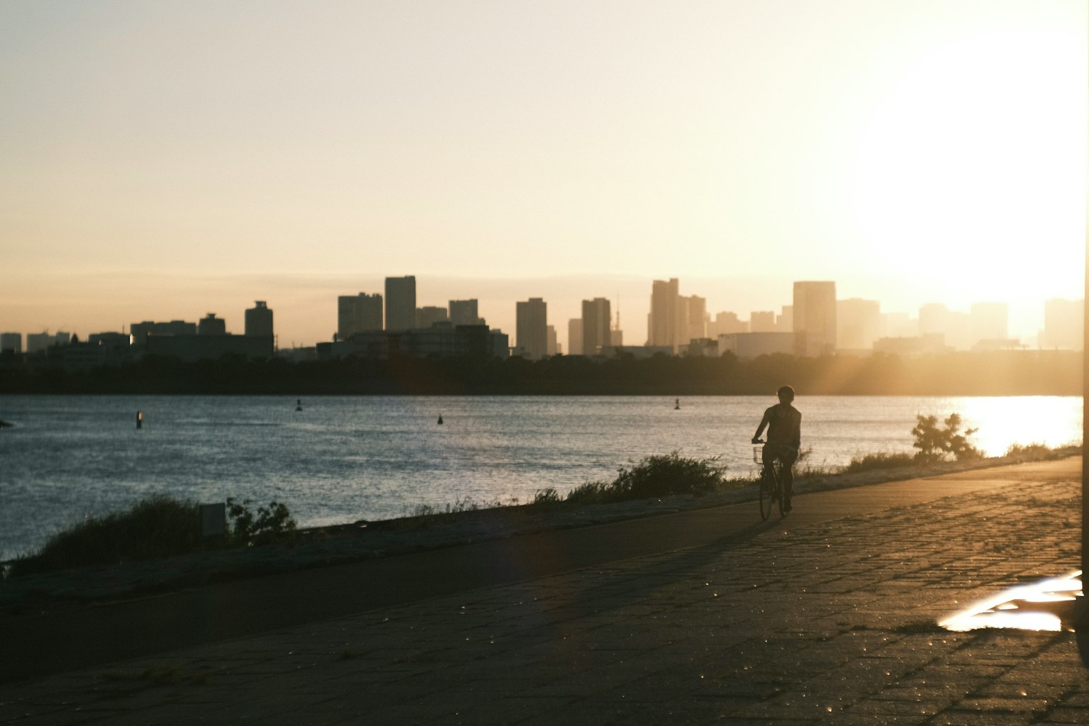 Silhouette d'une ville au coucher du soleil avec une promenade au bord de l'eau