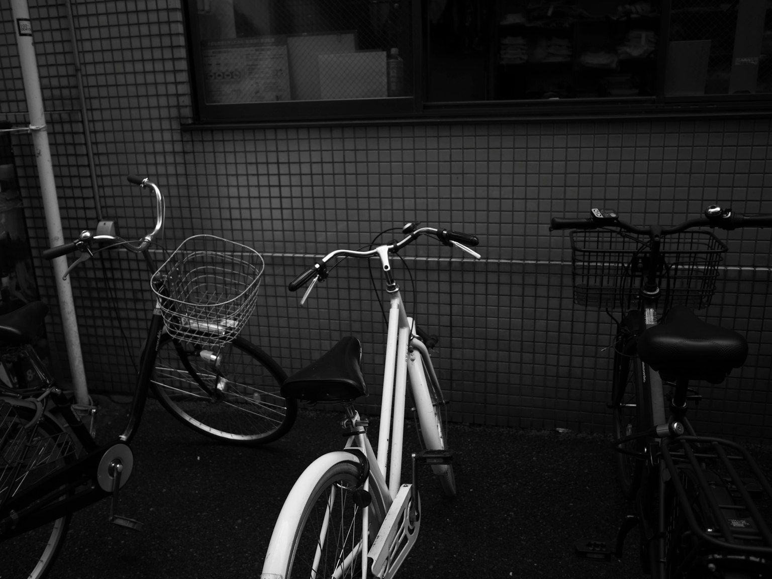 Scène avec un vélo blanc et un vélo noir avec un vélo à panier long visible