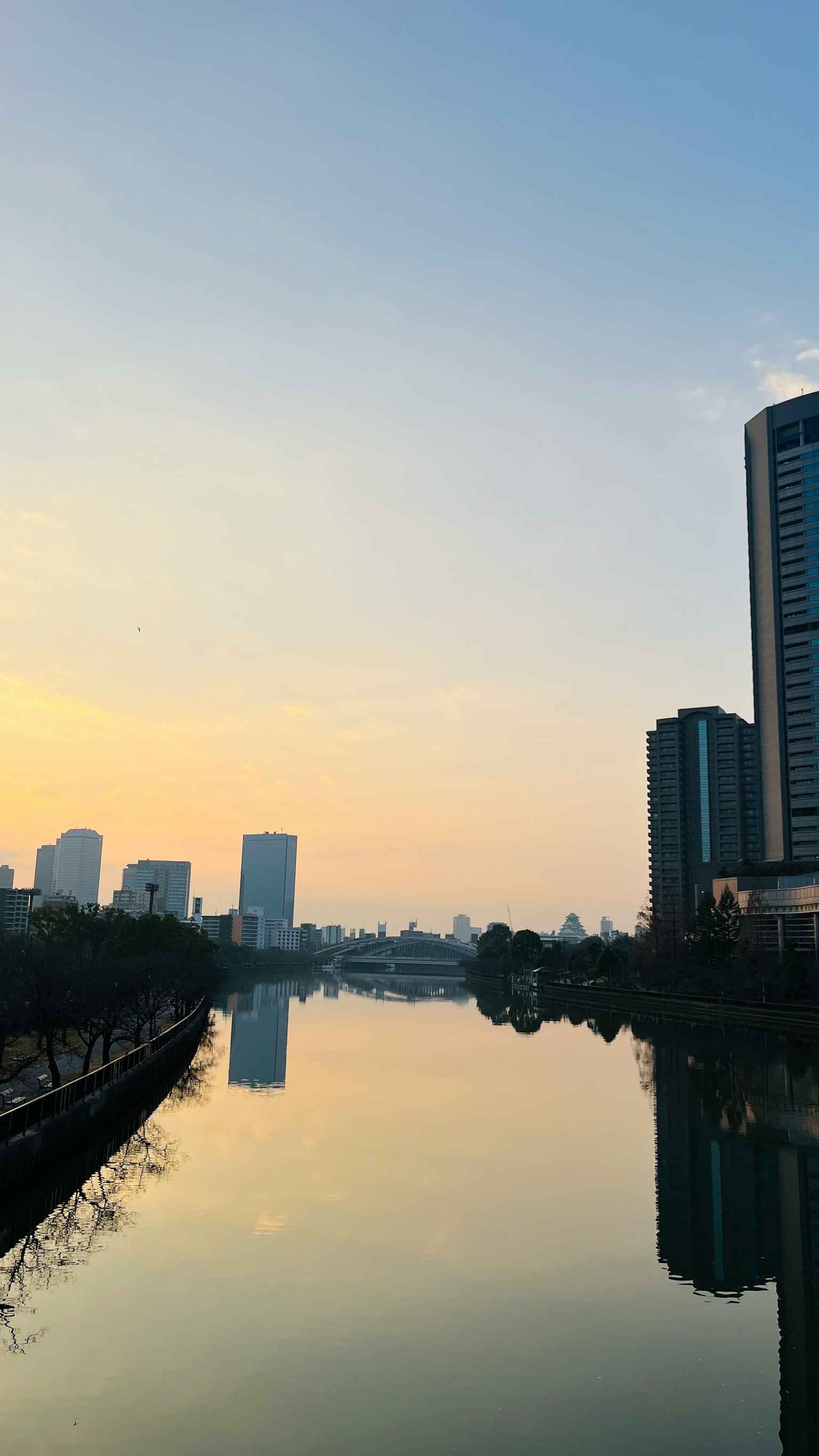 Pemandangan kota yang memantul di sungai saat matahari terbenam