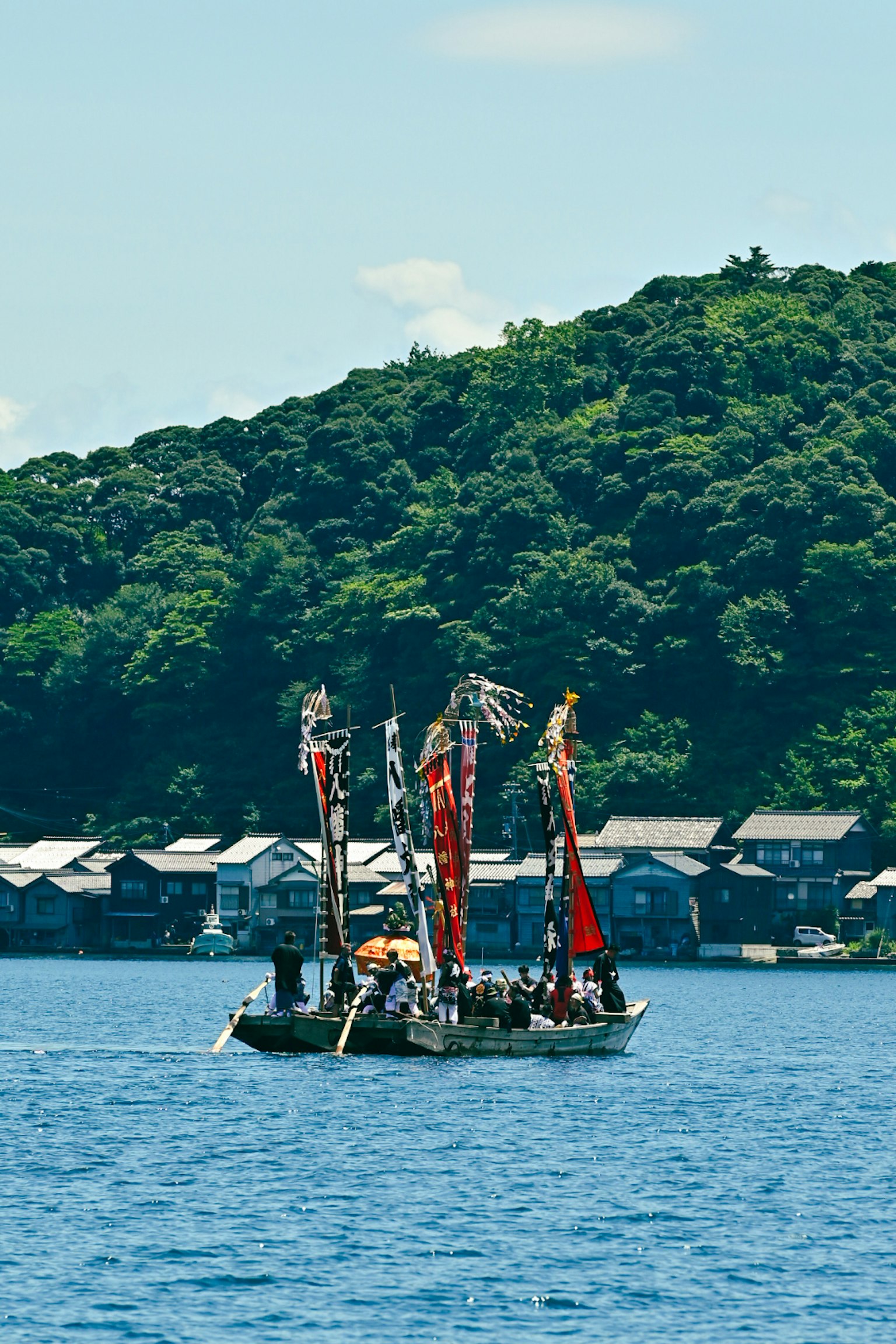 藍色湖面上的彩色帆船與綠色山脈背景
