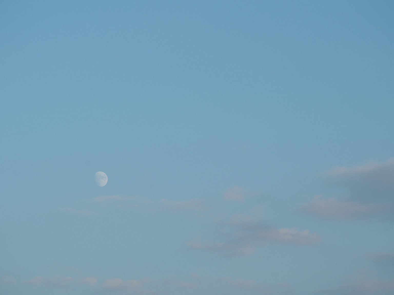 Blauer Himmel mit weißen Wolken und sichtbarem Mond
