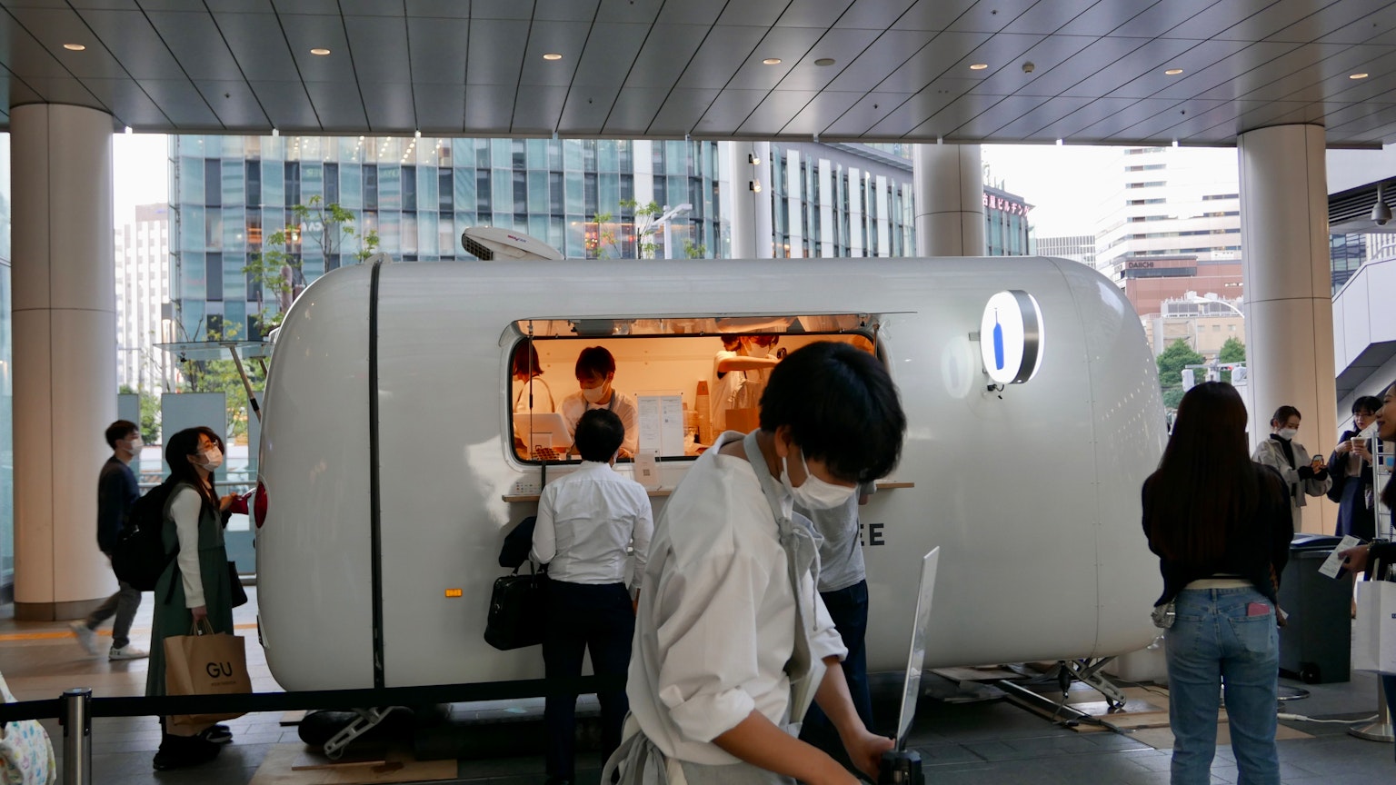Un camion di cibo bianco che serve clienti davanti a edifici urbani