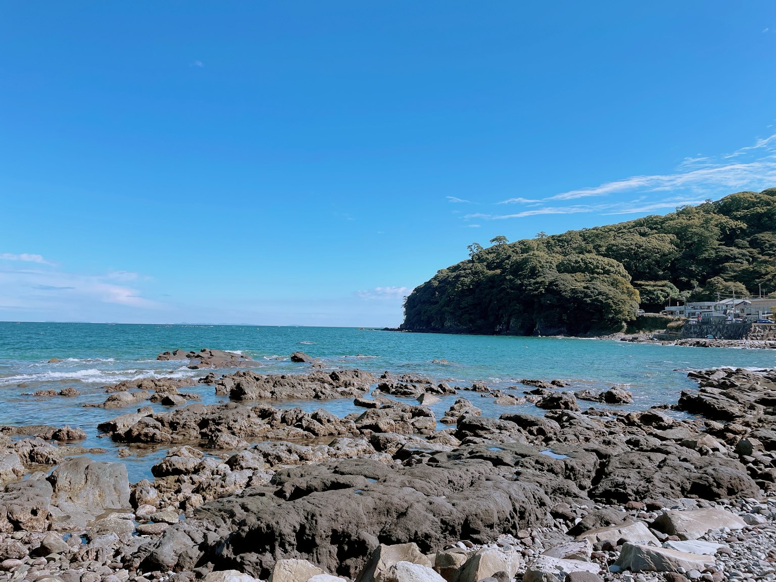 Scenic view of a rocky beach with blue sea and green hills in the background