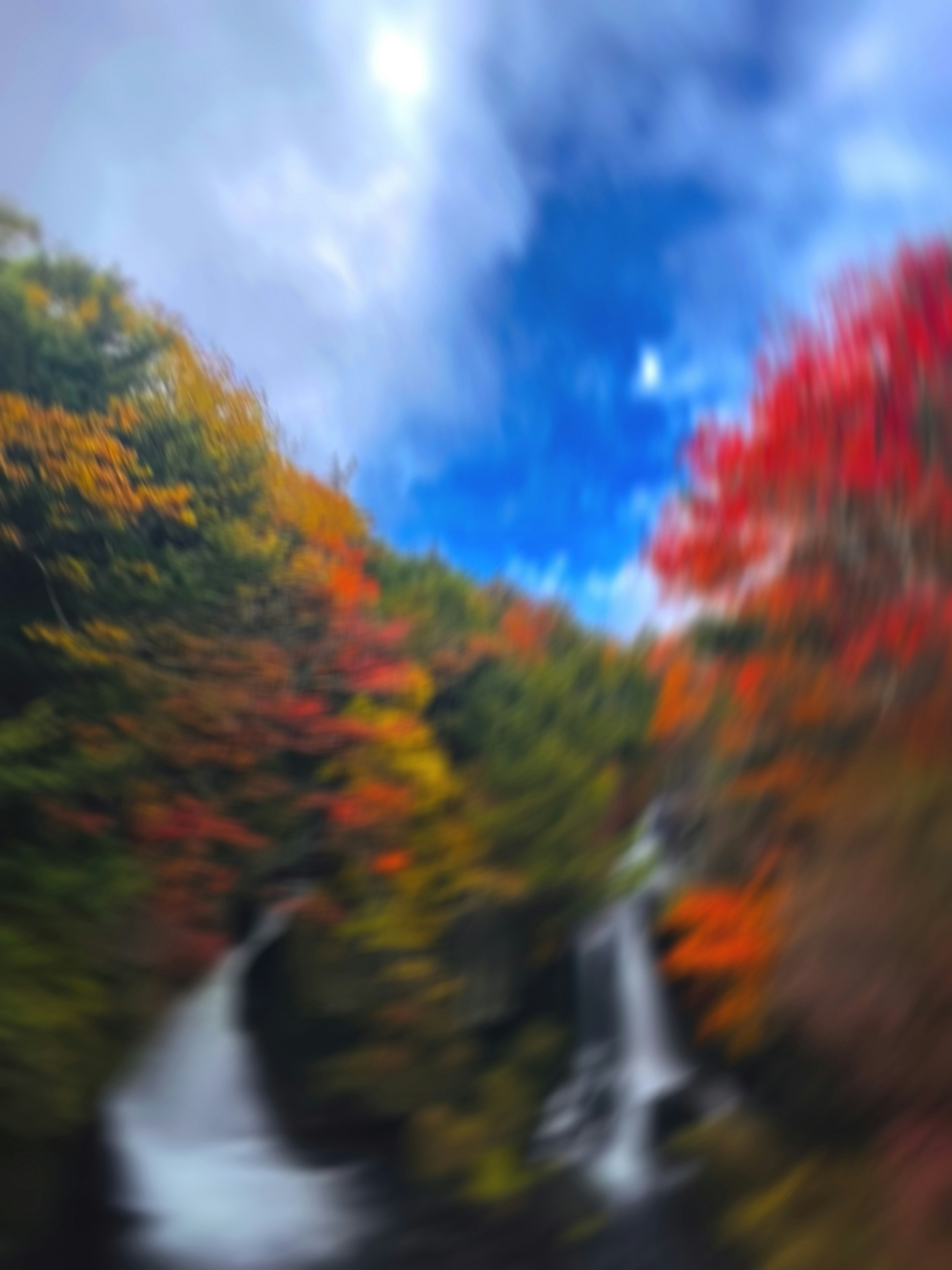 紅葉の山あいを流れる滝のある渓谷
