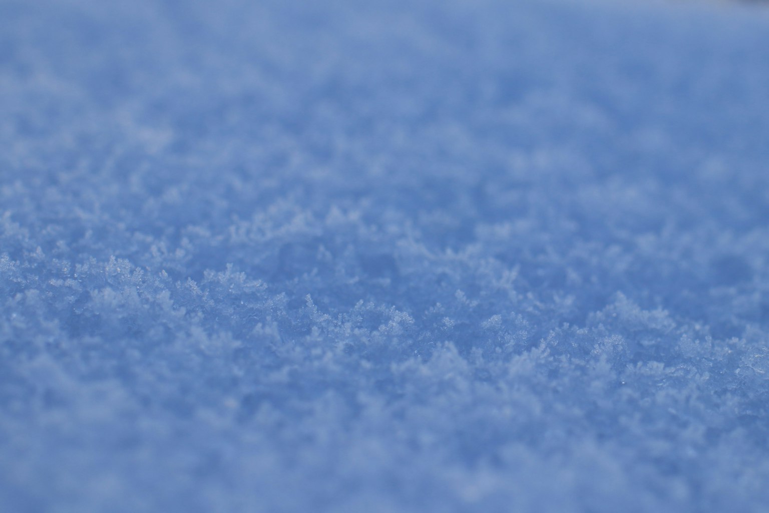 Gros plan de neige bleue mettant en valeur des flocons de neige fins